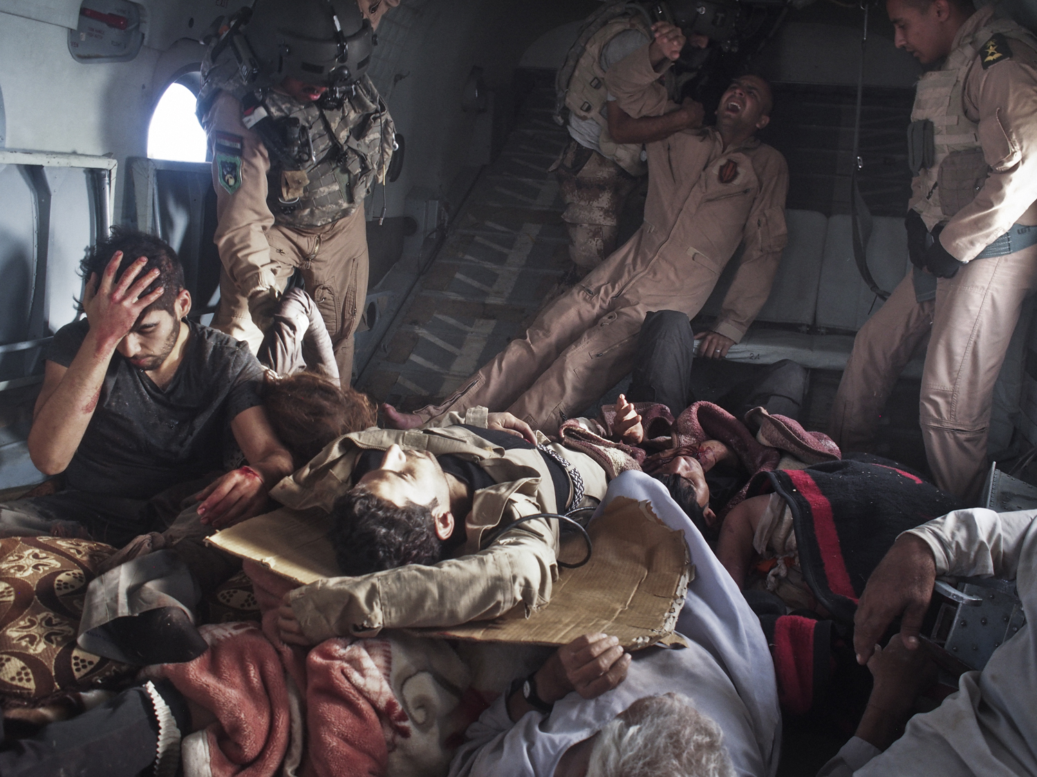 Aug. 12, 2014. Survivors of the Sinjar crash, including Yezidis and Kurdish and Iraqi military personnel, are loaded onto a second rescue helicopter bound for Kurdish territory. The pilot killed in the crash lies under the wounded.