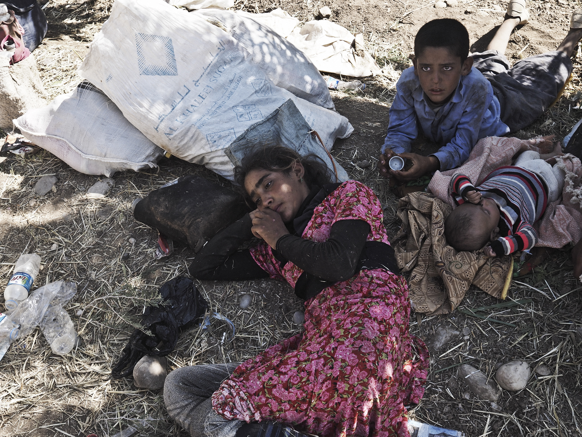 14-year-old Tawaf Ismail, a Yazidi girl from Sinjar, rests next to her brothers after arriving at the Fishkhabur border crossing between Iraq's Dohuk Province and Syria, Aug. 10, 2014.