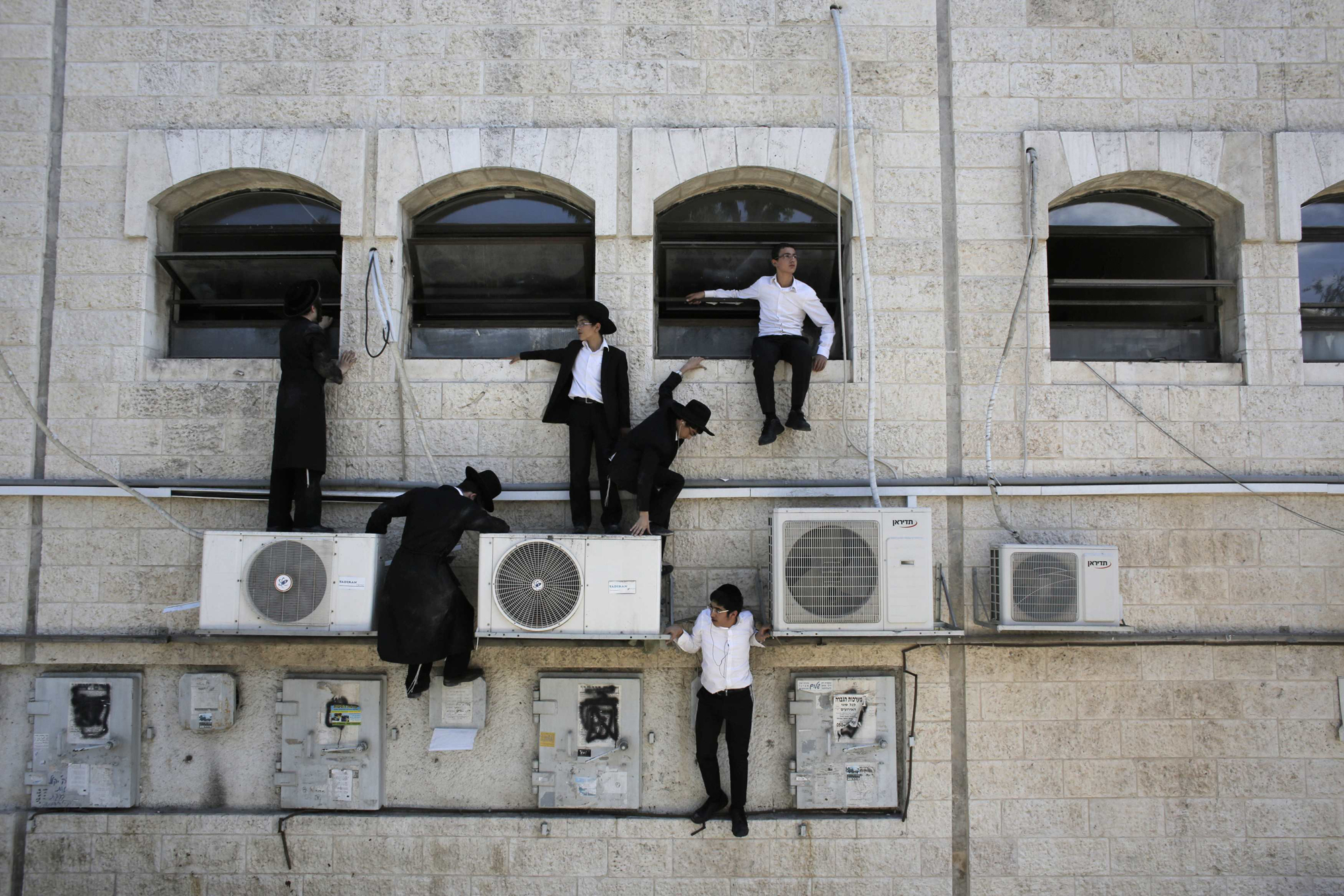 Ultra-Orthodox Jewish boys climb down a wall near the scene of a suspected attack in Jerusalem, Aug. 4, 2014.