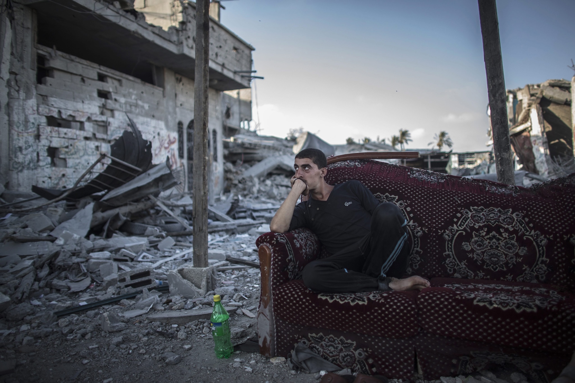A Palestinian sits on a salvaged sofa outside his destroyed home in the Shujayeh neighborhood, east of Gaza City, Aug. 6, 2014. (Oliver Weiken—EPA)
