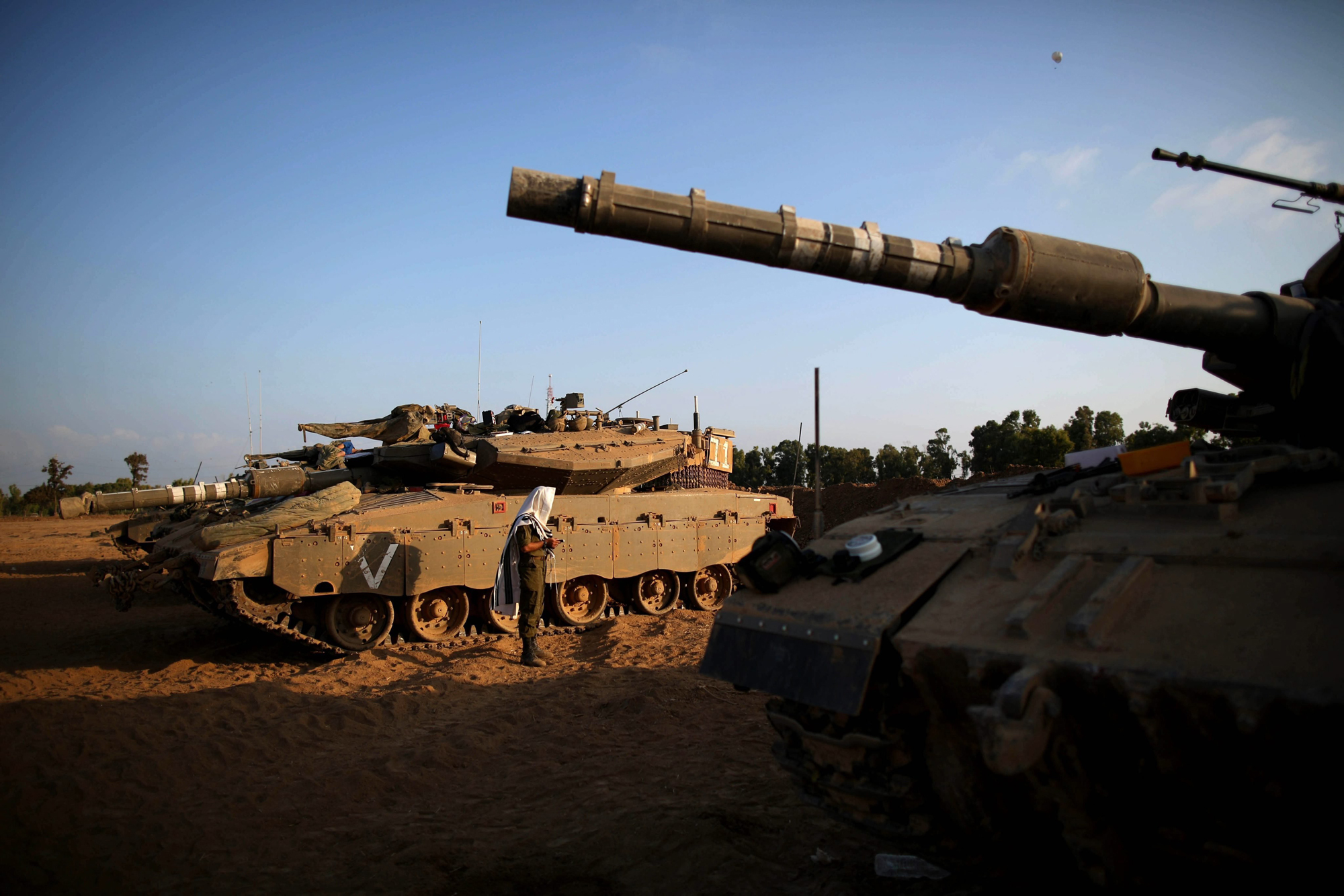 An Israeli soldier prays next to Merkava tanks at an unspecified location near the Israeli border with the Gaza Strip, Aug. 6, 2014.