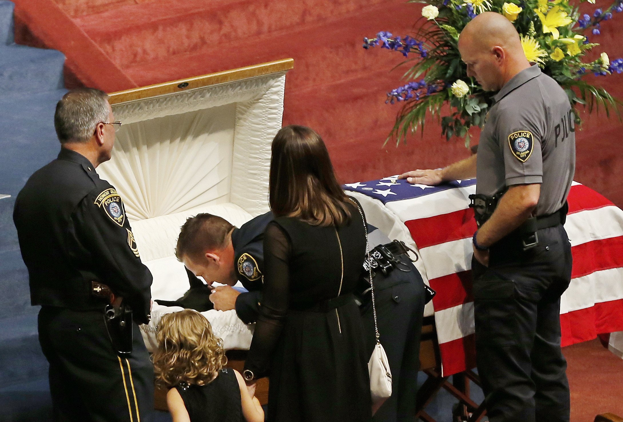 Oklahoma City police officer Sgt. Ryan Stark, center, leans over the casket of his canine partner, K-9 Kye, following funeral services for the dog in Oklahoma City, on Aug. 28, 2014. 