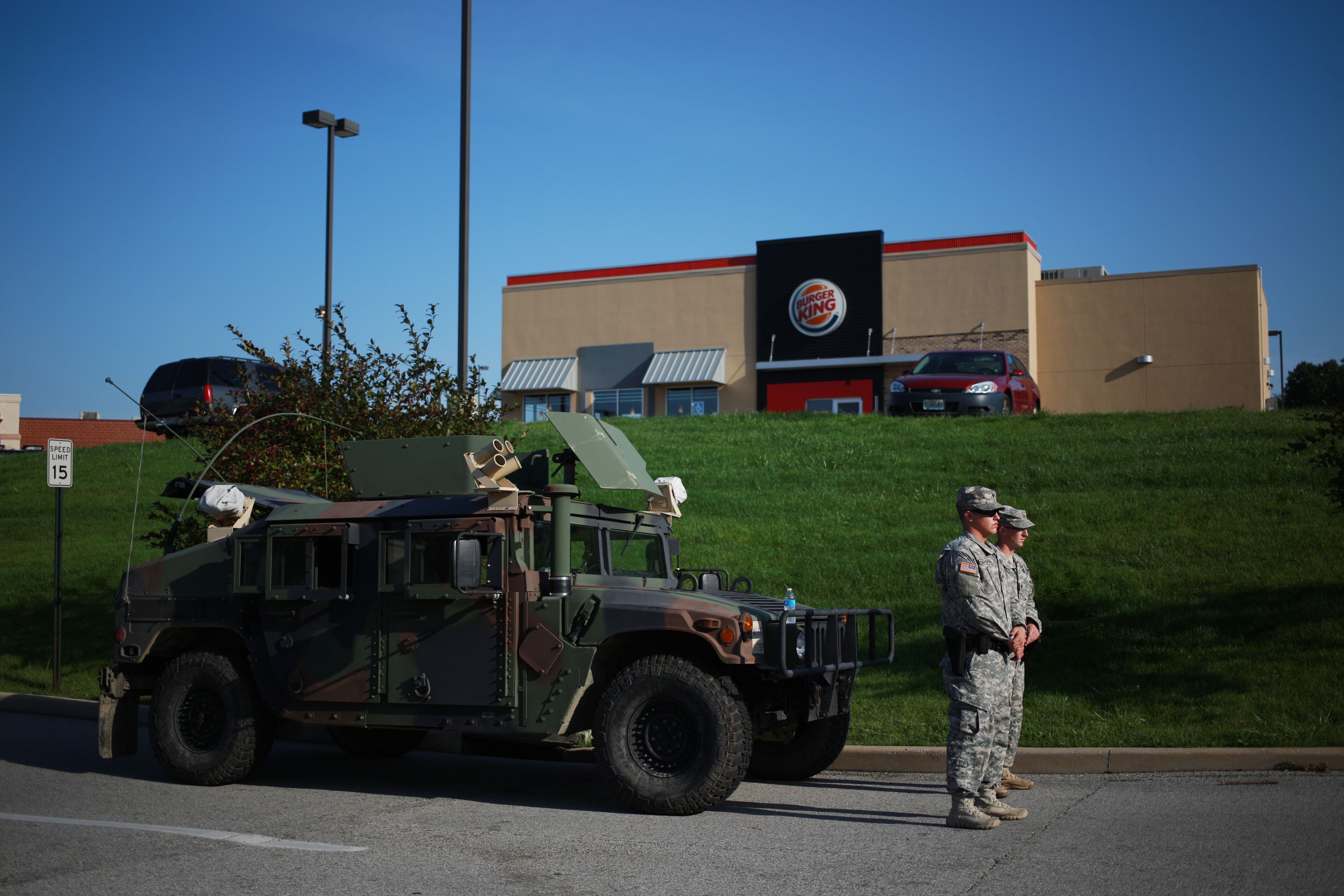 Soldiers from the Missouri National Guard stand in front of their Humvee vehicle outside a Burger King restaurant, operated by Burger King Worldwide Inc., as they man an entrance to a temporary police command center in Ferguson, Missouri, U.S., on Aug. 20, 2014.