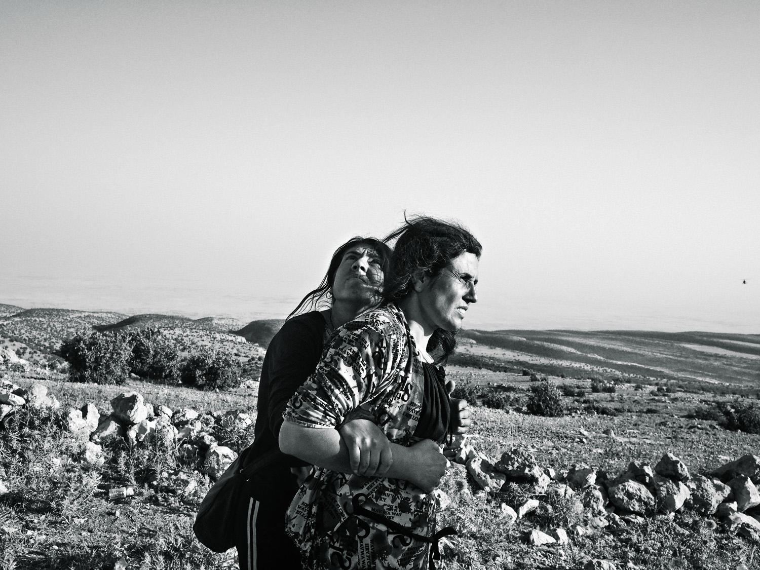 Yazidi women who fled from ISIS into Iraq’s  Sinjar Mountains wait for the arrival of a rescue helicopter (Moises Saman—Magnum for TIME)