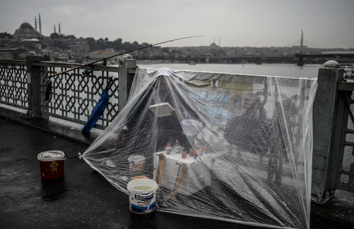 Aug. 9, 2014 A fisherman protects himself from a rain on the Galata bridge during a rainy morning on in Istanbul.
