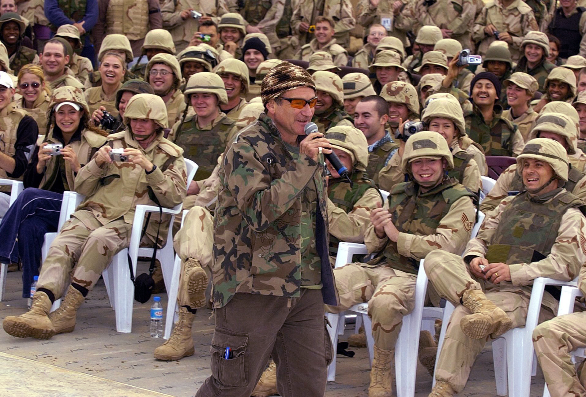 Robin Williams wears a camouflage jacket while entertaining a cheering crowd of US troops as part of a United Service Organiztions (USO) Holiday Tour at the International Airport in Baghdad, Dec. 16, 2003. (Mike Theiler—EPA)