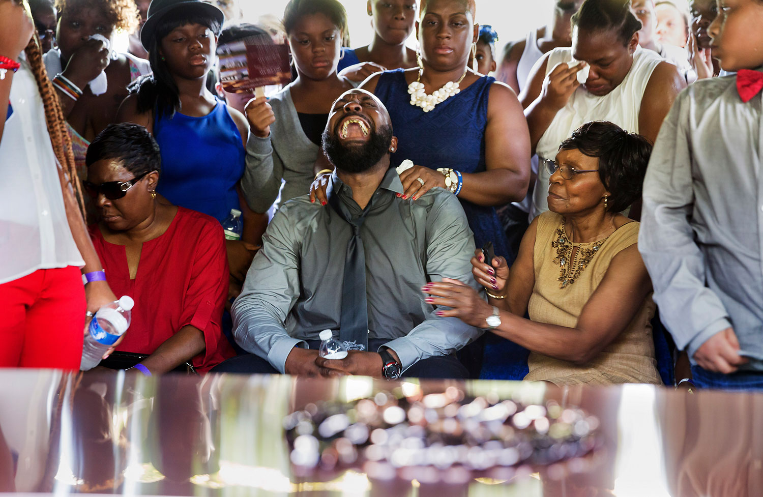 Michael Brown Sr, yells out as his son's  casket is lowered into the ground at St. Peter's Cemetery in St. Louis