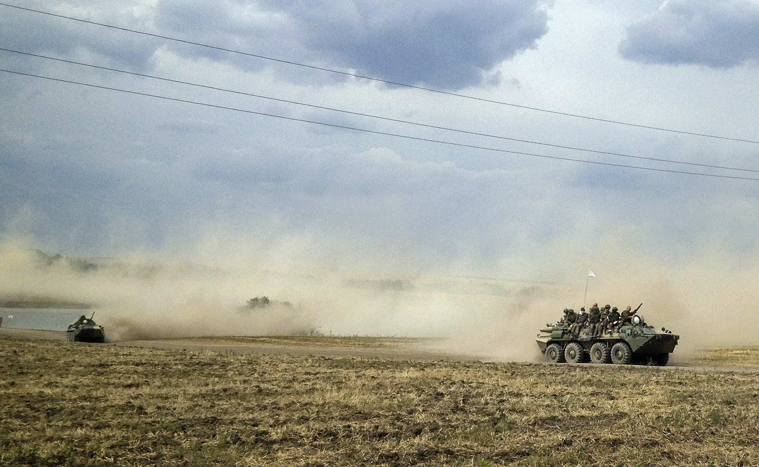 Servicemen sit atop an armoured vehicle as they travel through the steppe near the village of Krasnodarovka in Rostov region