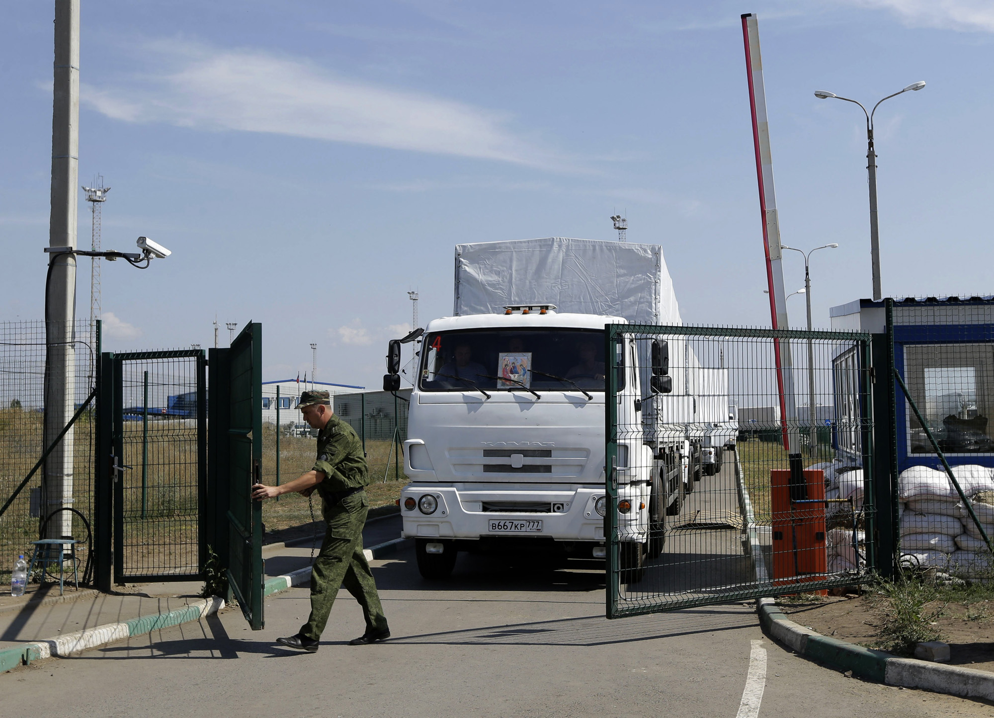 A Russian border guard opens a gate into the Ukraine for the first trucks heading into the country from the Russian town of Donetsk, Rostov-on-Don region, Russia,  Aug. 22, 2014. (Sergei Grits—AP)