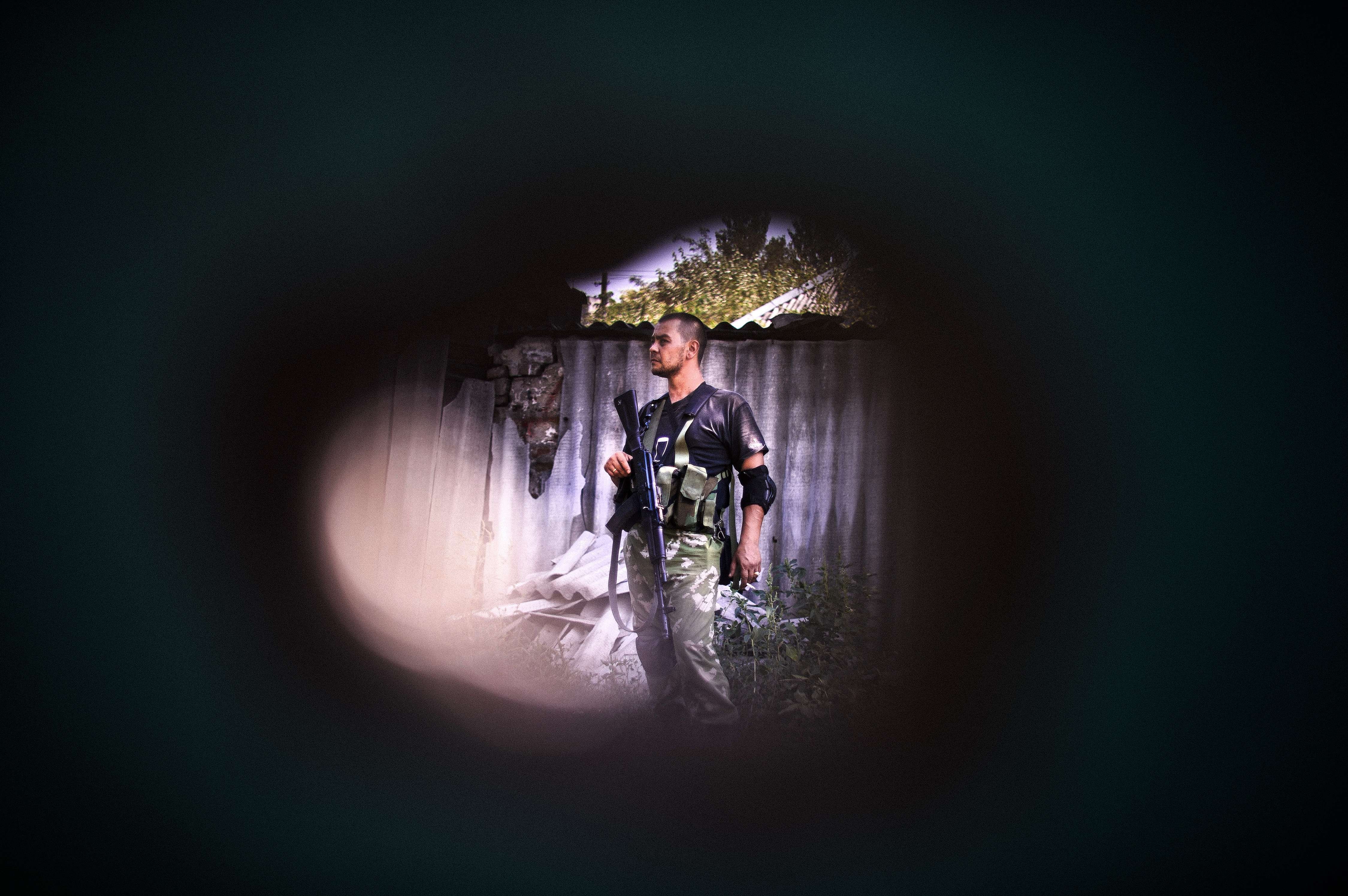 A pro-Russian gunman is seen through a shrapnel hole after shelling in Donetsk on August 22, 2014. (Dimitar Dilkoff—AFP/Getty Images)