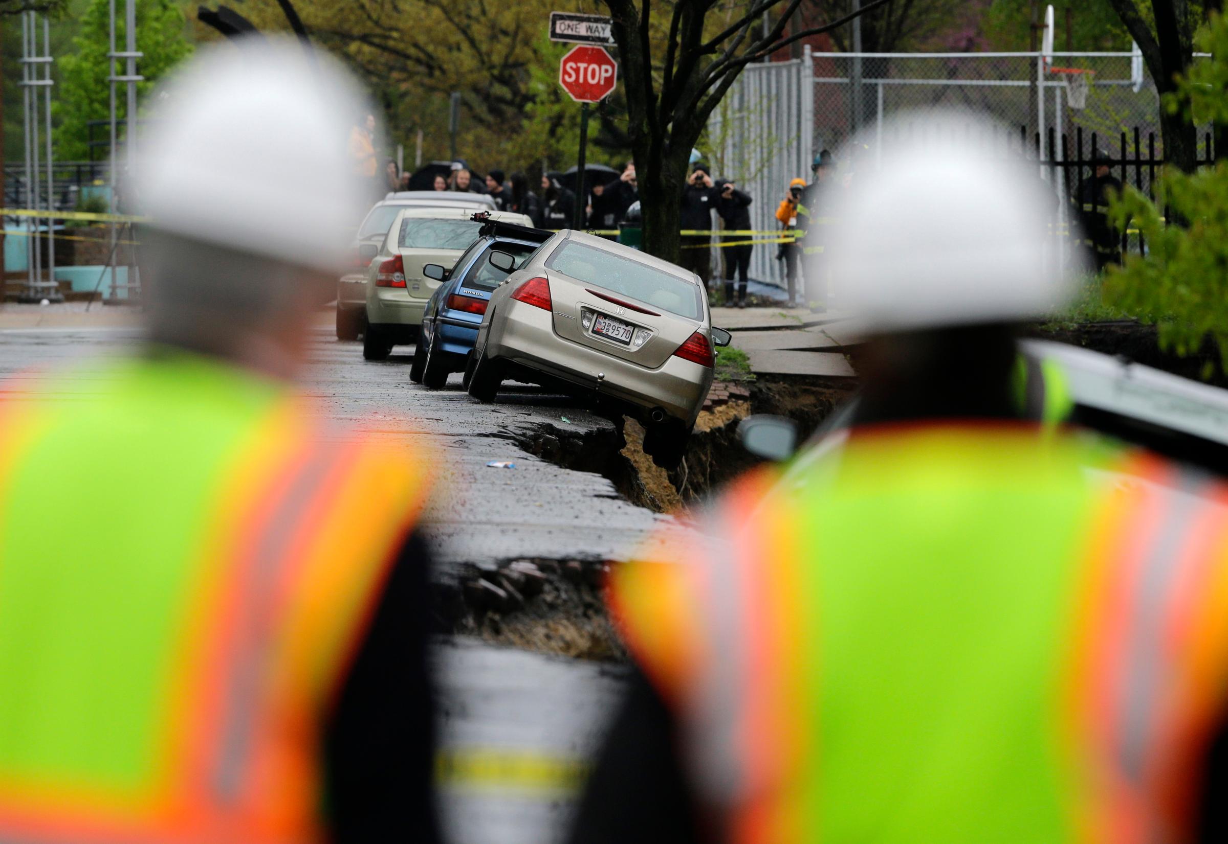 Emergency officials approach cars on the edge of a sinkhole in Baltimore, April 30, 2014.