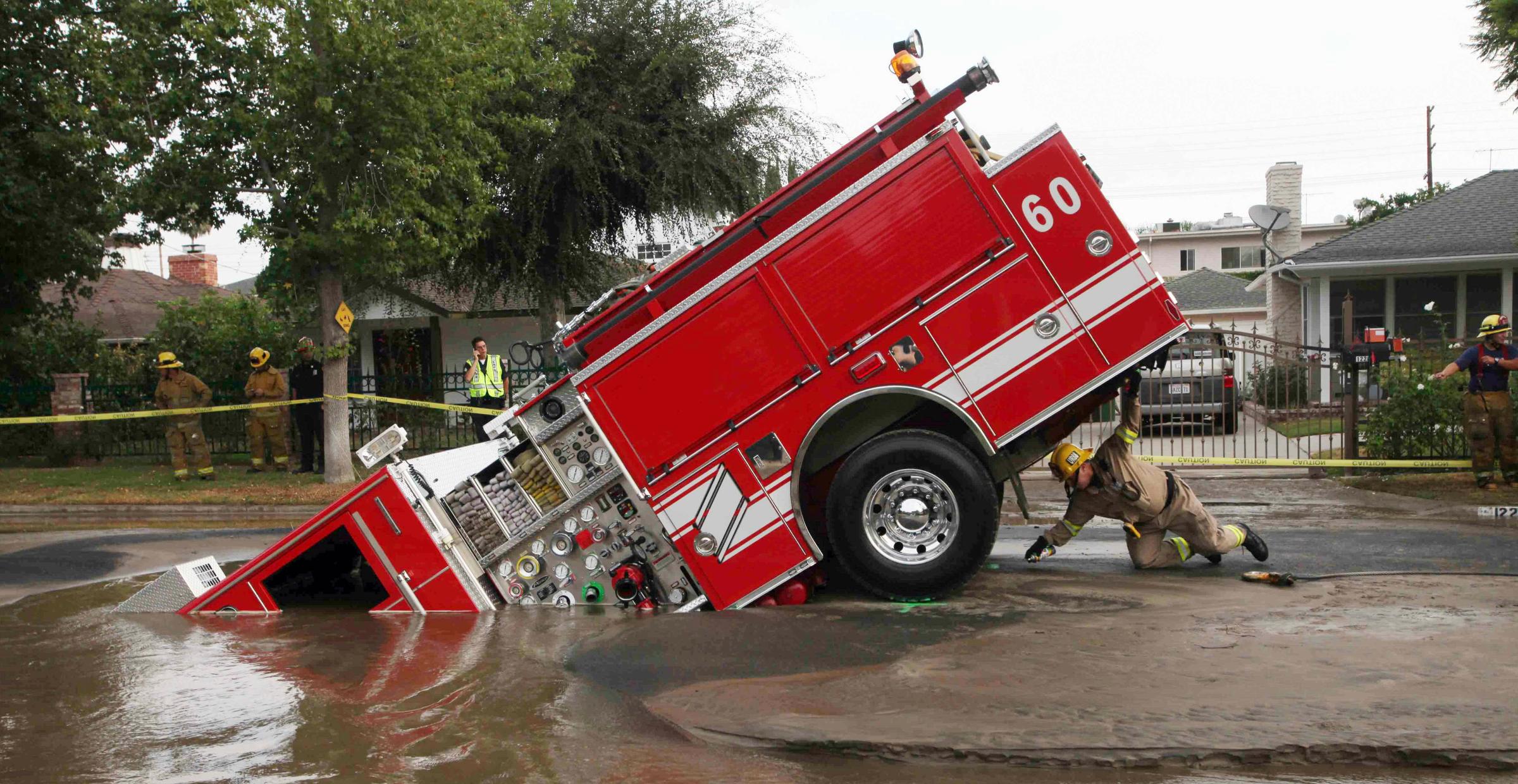 A Los Angeles fireman looks under a fire truck stuck in a sinkhole in the Valley Village neighborhood of Los Angeles, Sept. 8, 2009. Four firefighters escaped injury early Tuesday after their fire engine sunk into a large hole caused by a burst water main in the San Fernando Valley, authorities said.