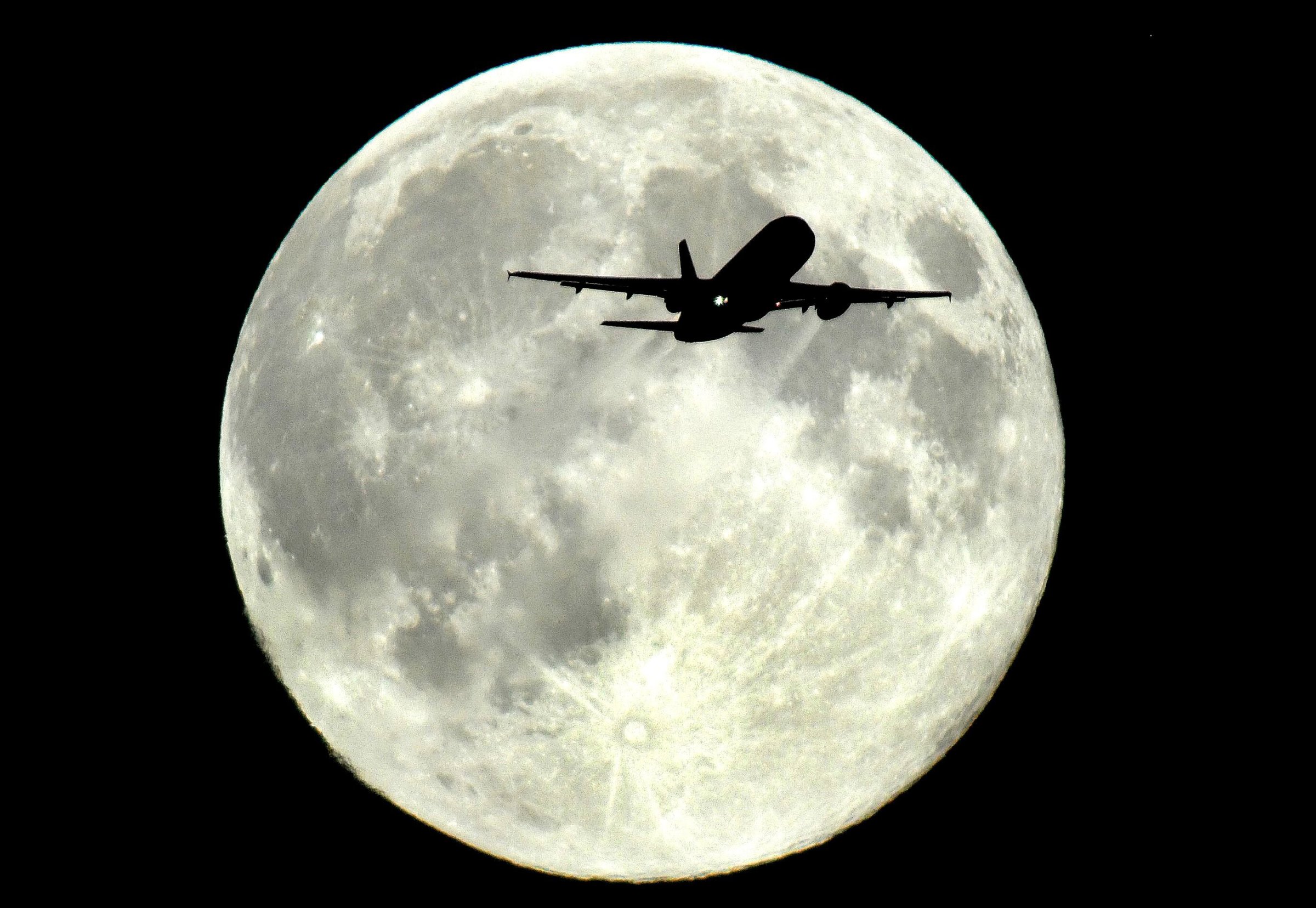 A plane flies in front of a supermoon above Westminster in London enroute to Heathrow airport on August 10, 2014.