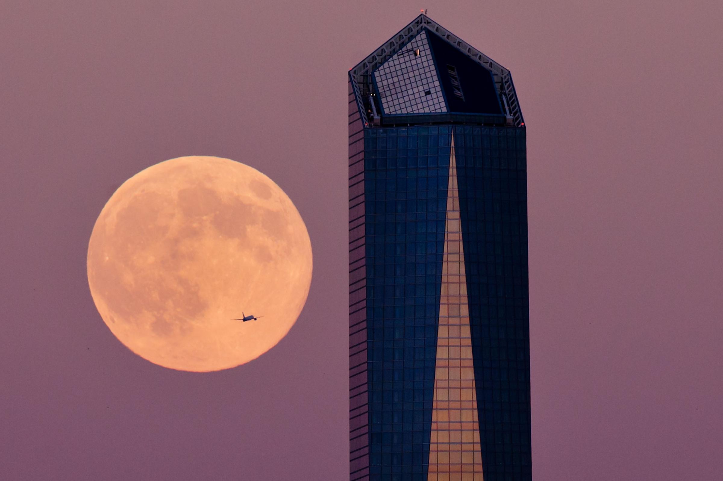 A plane flys across the supermoon surrounded by a Madrid skyscraper on August 9, 2014 in Madrid.