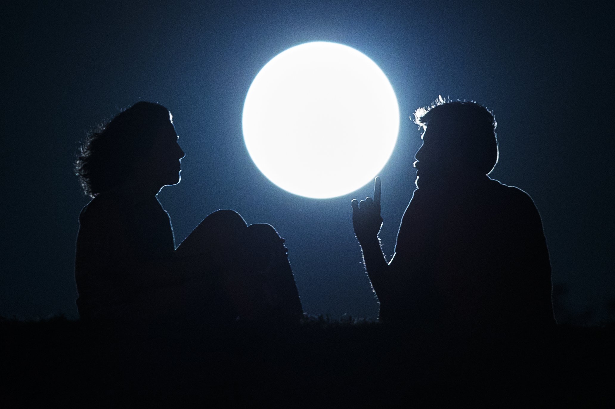 A couple talk as they sit against the perigee moon, also known as a supermoon, in Madrid on August 10, 2014.
