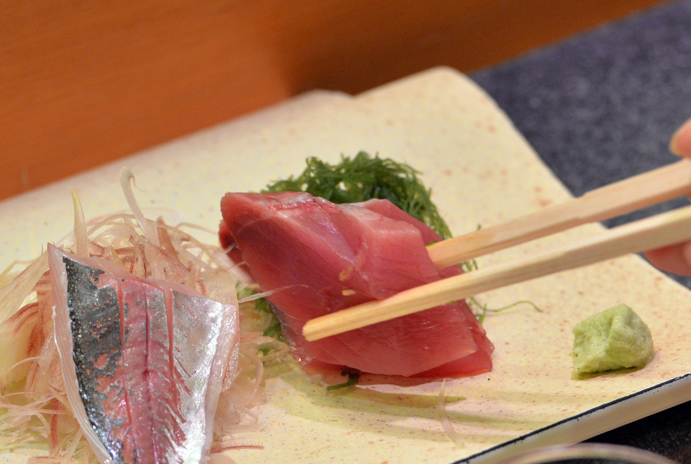 A customer eats bonito and horse mackerel sashimi (raw fish) at a high-end sushi restaurant in Tokyo on  July 16, 2013.