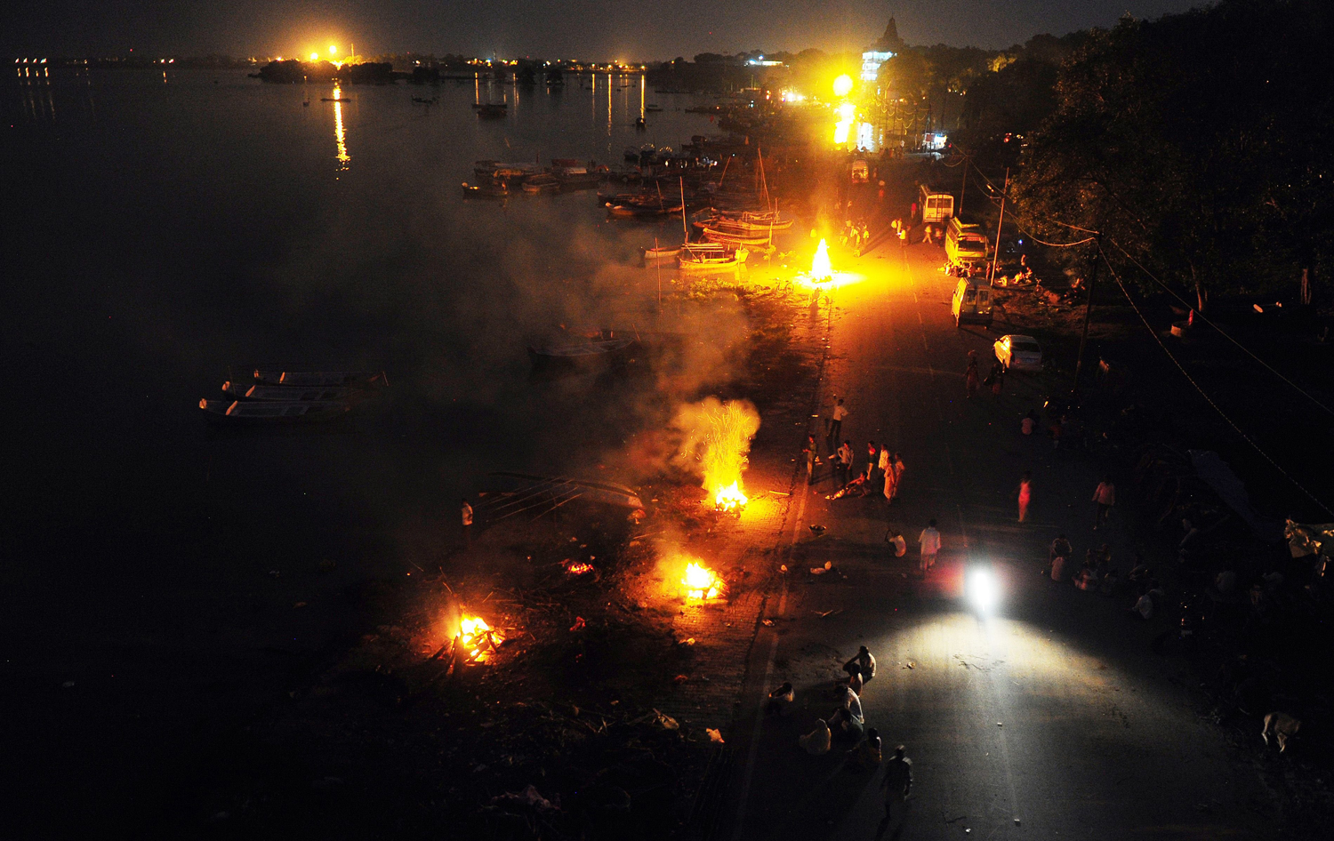 Aug.10, 2014. Indian residents hold cremations for the dead along a roadside following heavy flooding at Daraganj ghat near Sangam in Allahabad.