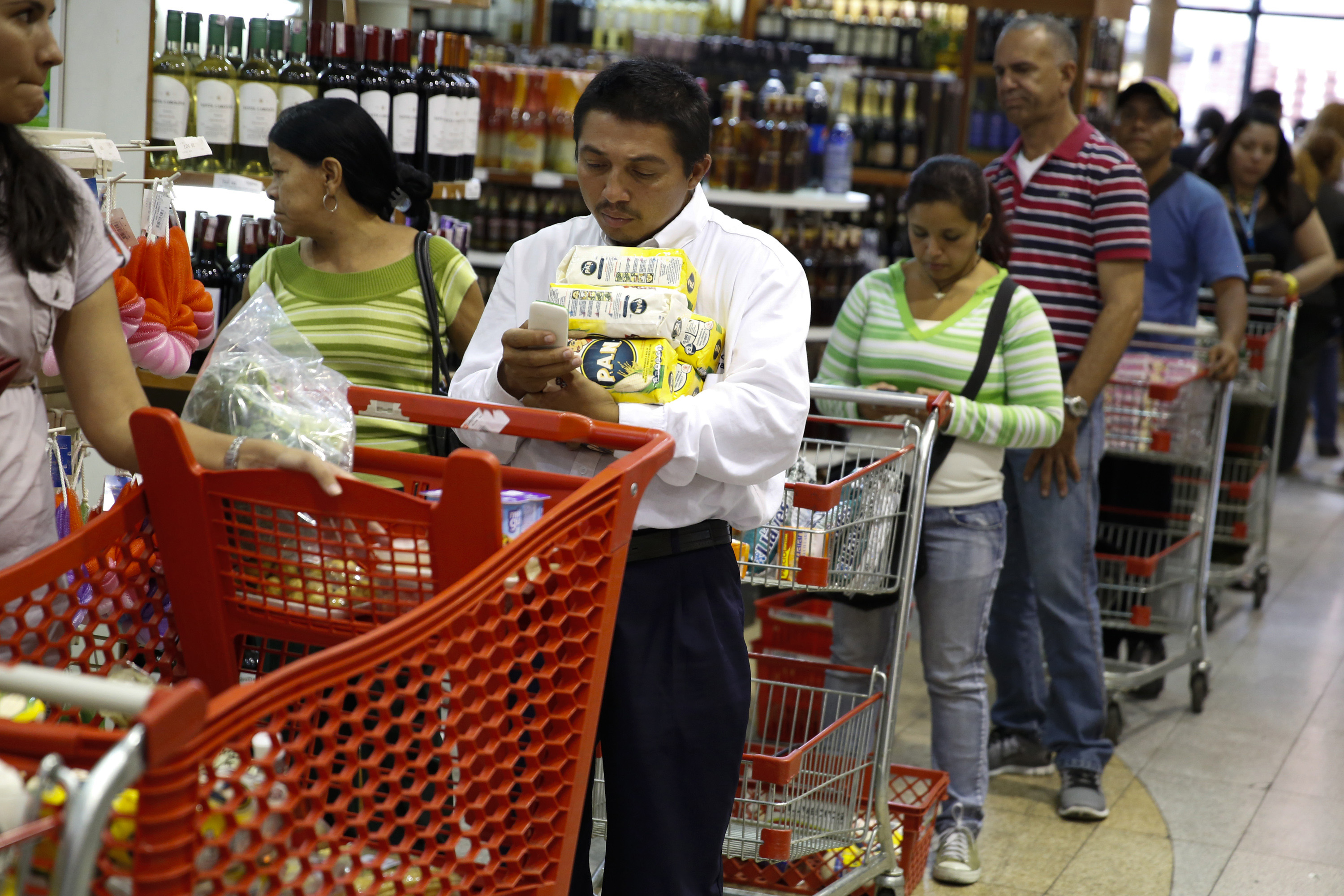 People stand at the checkout line at a supermarket in Caracas