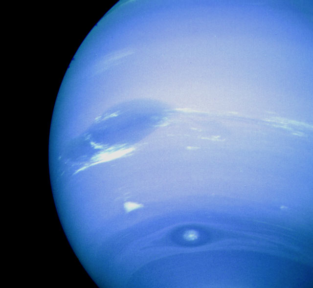 A color image of Neptune's Great Dark Spot, accompanied by white high-altitude clouds taken from the Voyager 2 spacecraft. (NASA)