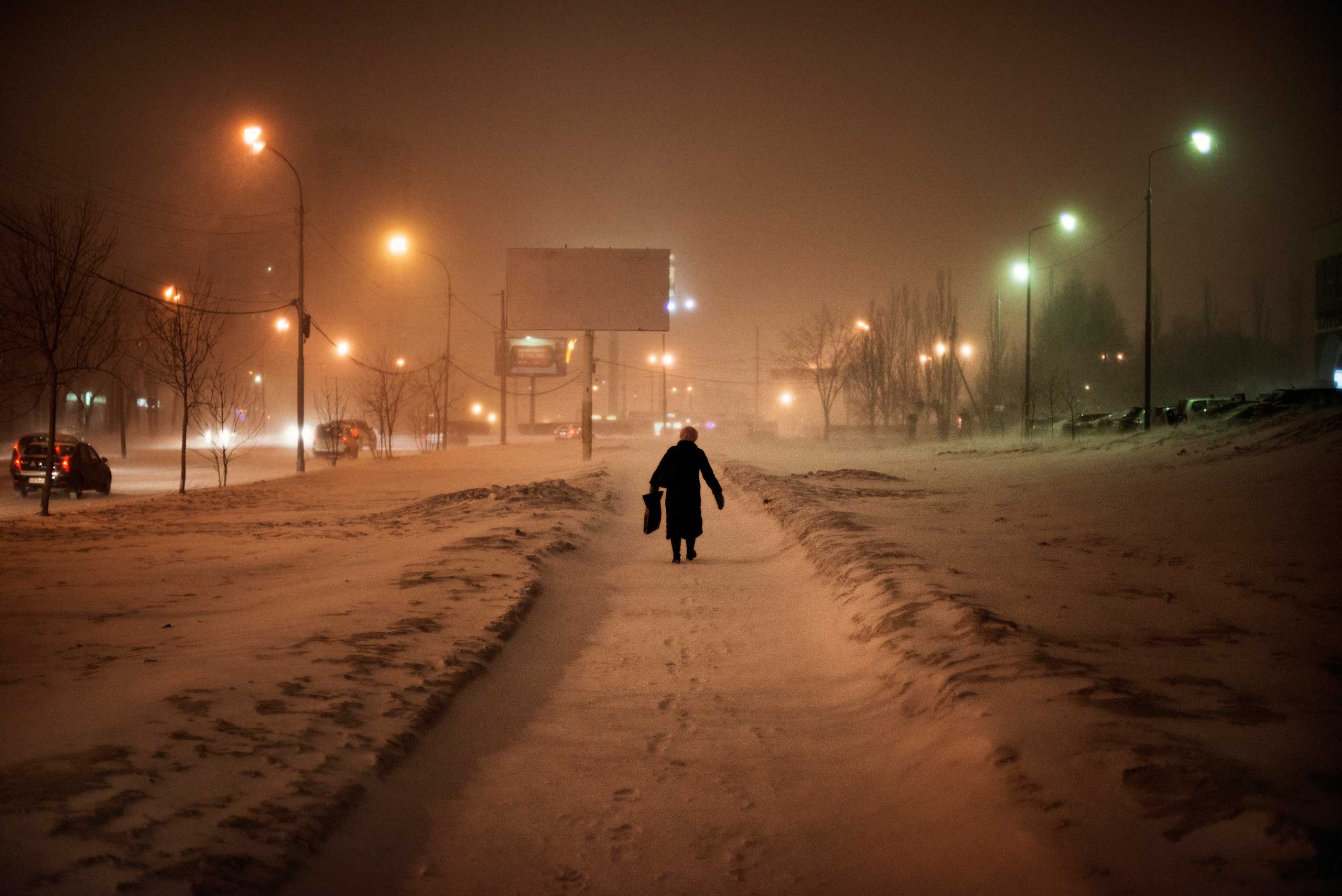 A woman walks at night on a street in Yekaterinburg during a snow storm.