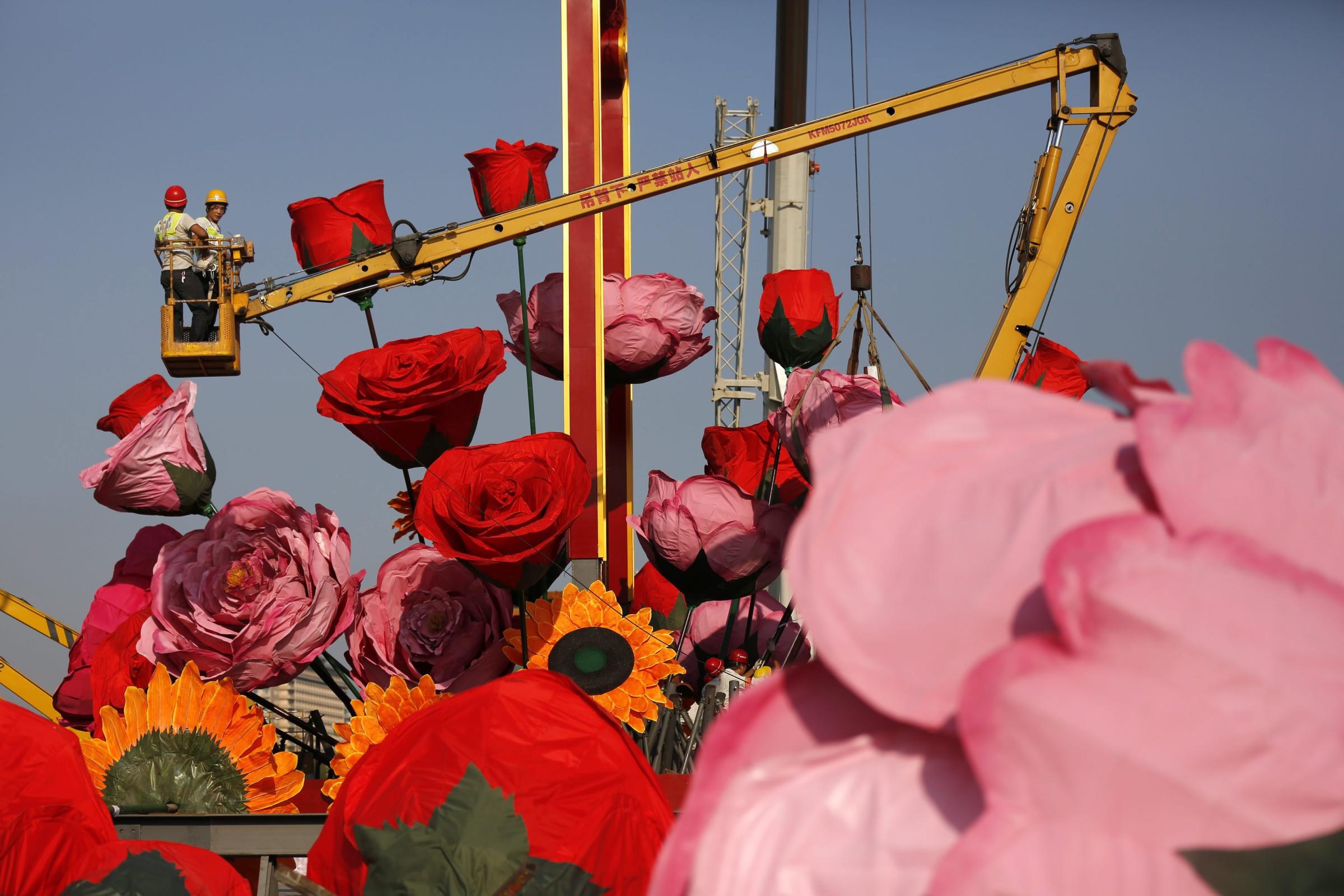 Chinese workers set up giant decoration flowers in preparation for National Day at Tiananmen Square in Beijing, China on Sept. 18, 2014.