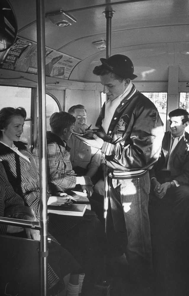 Writing poetry, Earl jots down inspiration in bus. His poems in the school paper are signed "Elbow Reum." After graduation he plans to study for priesthood.