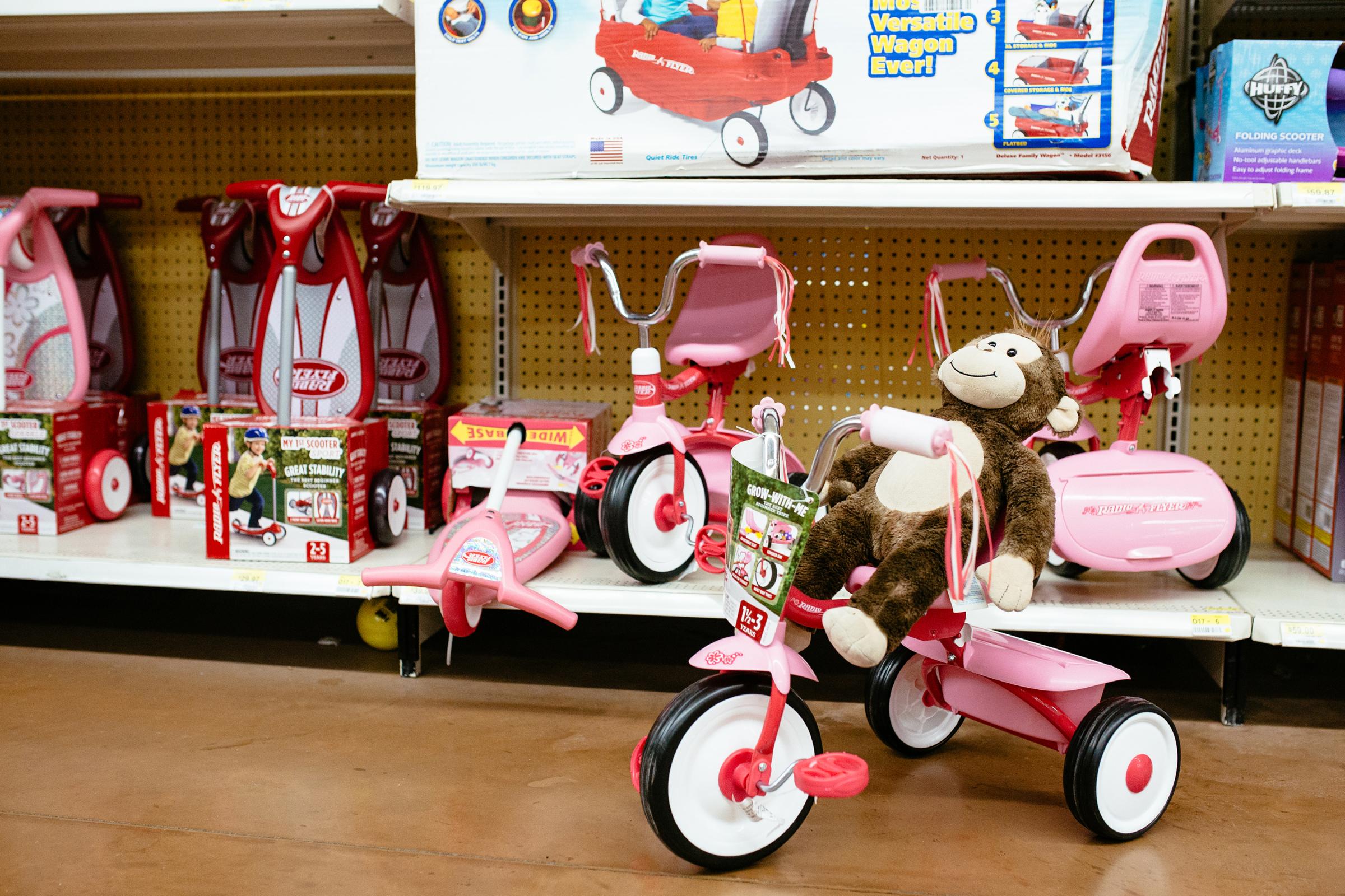 George the Monkey on a pink tricycle in the toy store