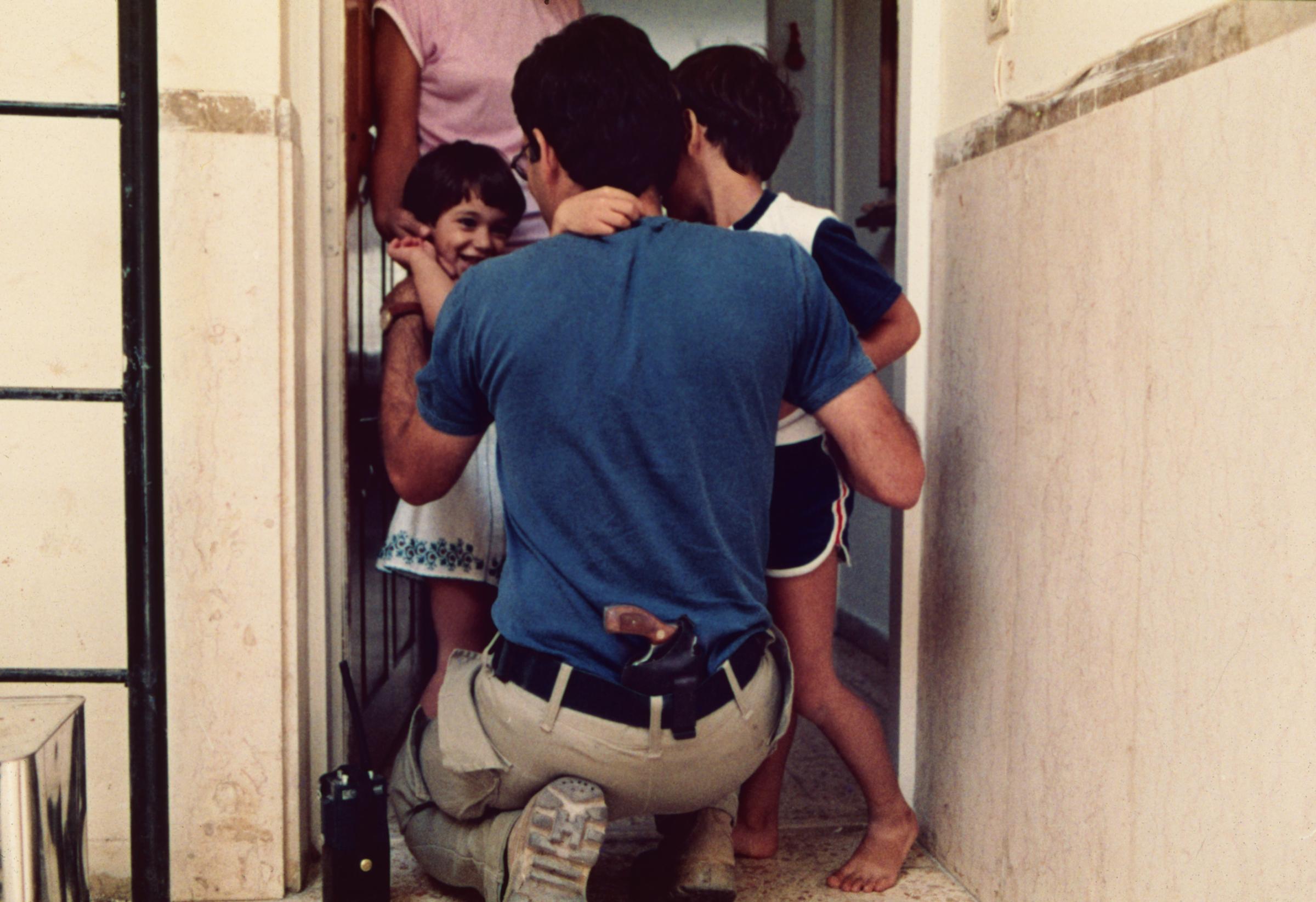 Uri, an Israeli bomb squad officer, says goodbye to his children in the morning. [1984]