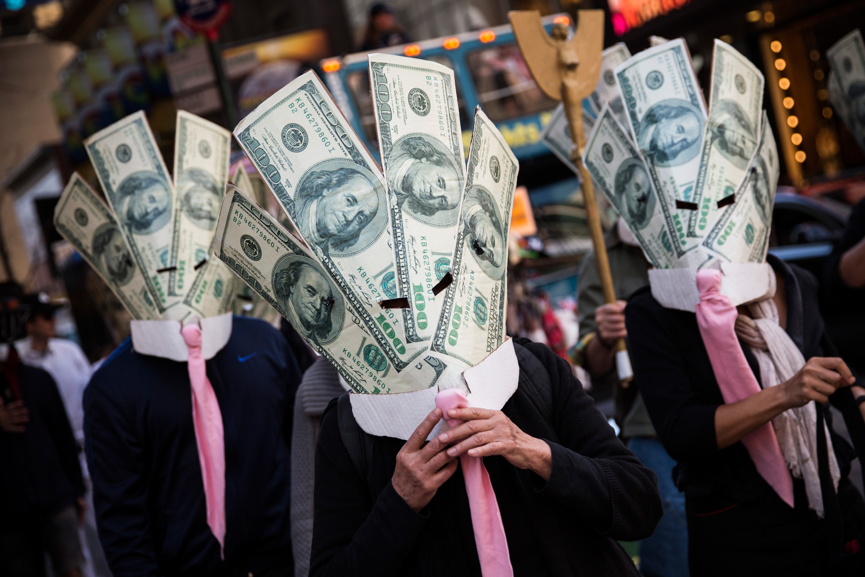 Occupy Wall Street protesters wearing masks made out of enlarged dollar bills act in a short skit in Times Square in New York City on Sept. 17, 2013 (Andrew Burton—Getty Images)