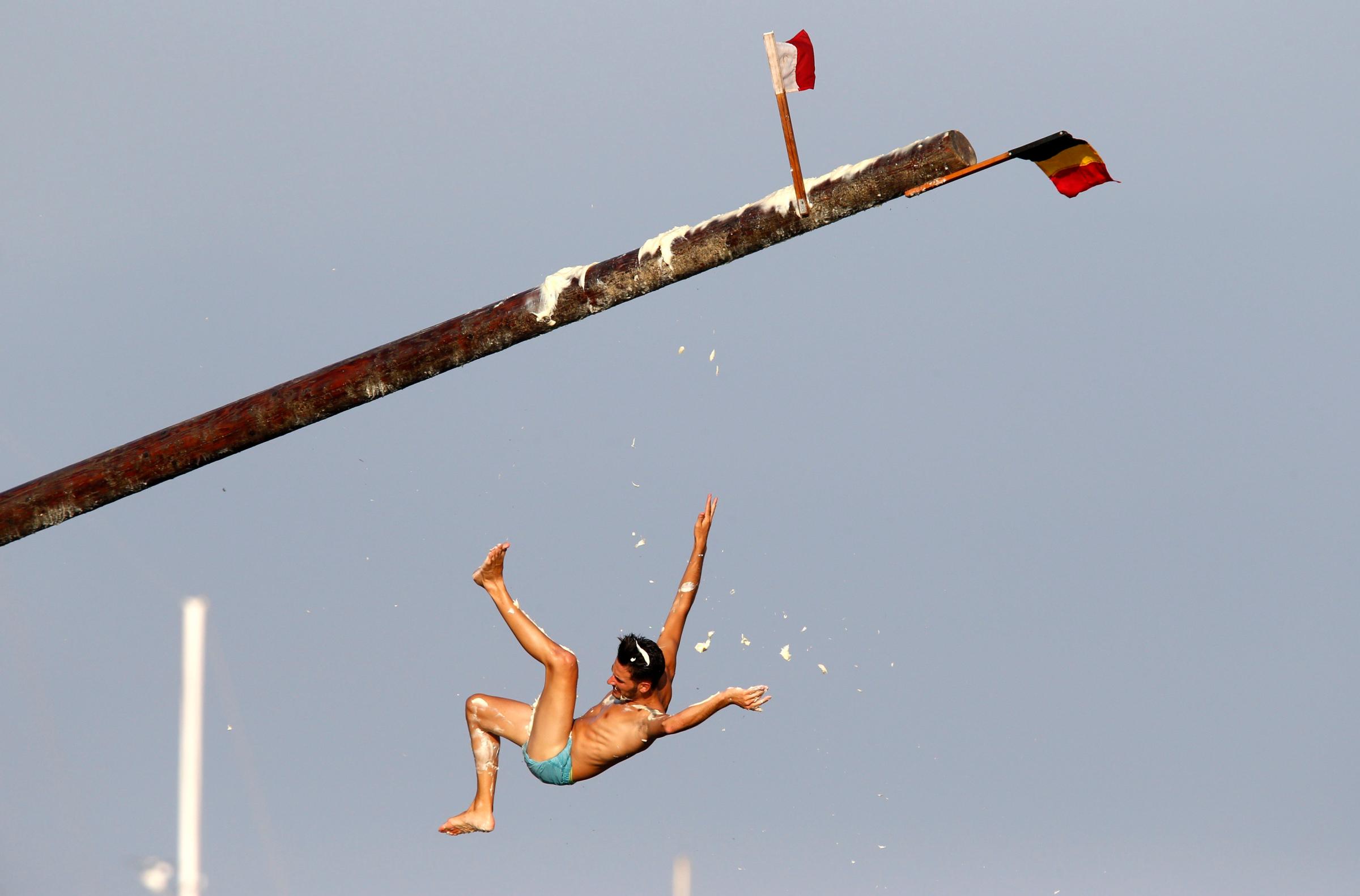 A man falls off the "gostra", a pole covered in grease, during the celebrations for the religious feast of St Julian, patron of the town of St Julian's, outside Valletta on Aug. 31, 2014.