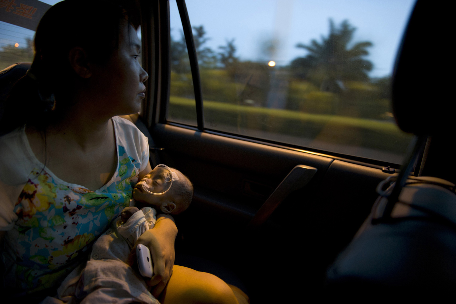 Wu, holds her daughter Yuanyuan, who is suffering from an unknown disease, as she looks out of the window on a taxi in Shenzhen