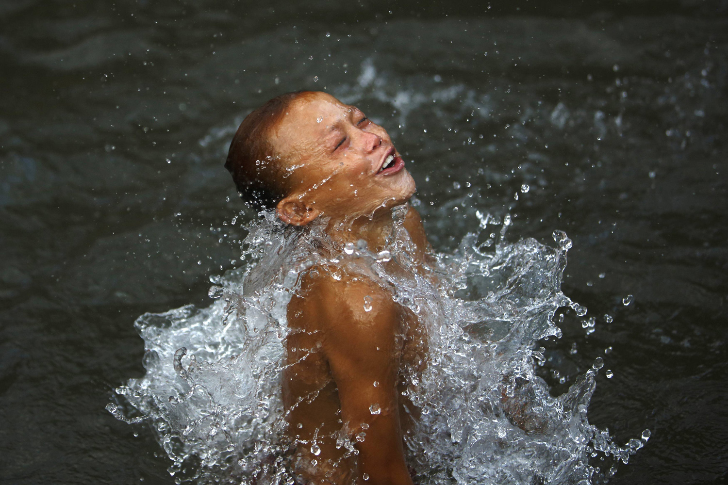 A boy swims in a pond in Lalitpur