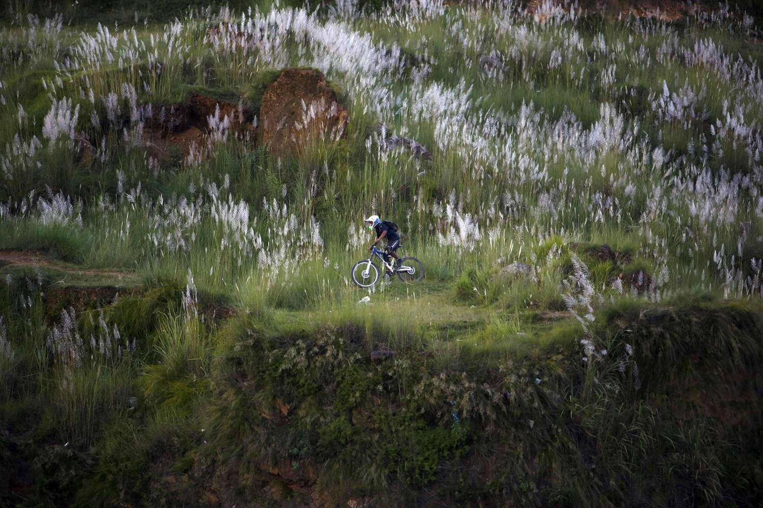 A youth rides a bicycle on the hills in Kathmandu, Nepal on Sept. 3, 2014.