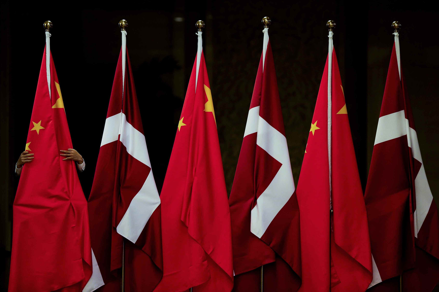 A worker arranges China's and Denmark's national flags displayed outside a room as he prepares for a meeting between the visiting Danish Prime Minister Thorning-Schmidt and Chinese President Xi (both not pictured) at the Great Hall of the People in Beijin