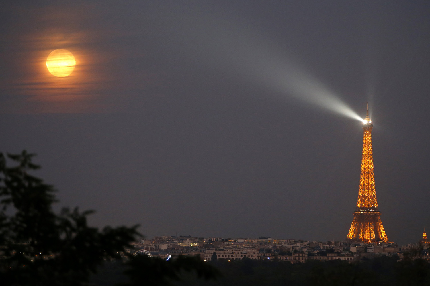A super moon rises in the sky near the Eiffel tower as seen from Suresnes, Western Paris on Sept. 9, 2014.