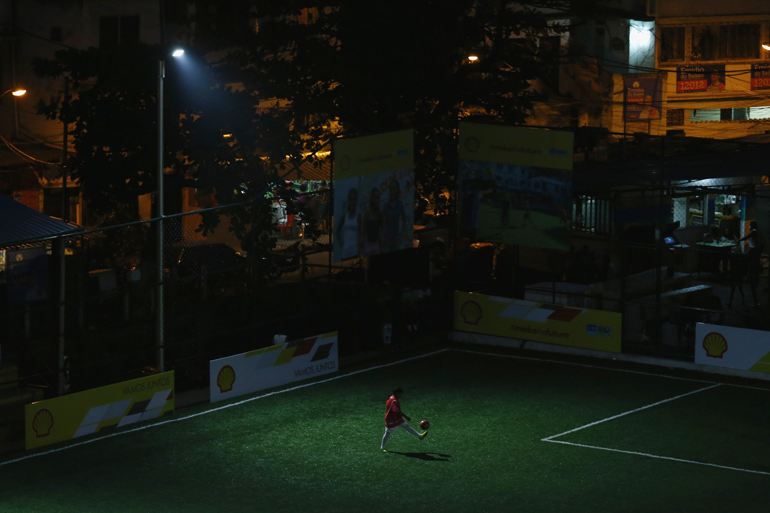 Kid plays with soccer ball at a refurbished soccer field at the Mineira slum in Rio de Janeiro