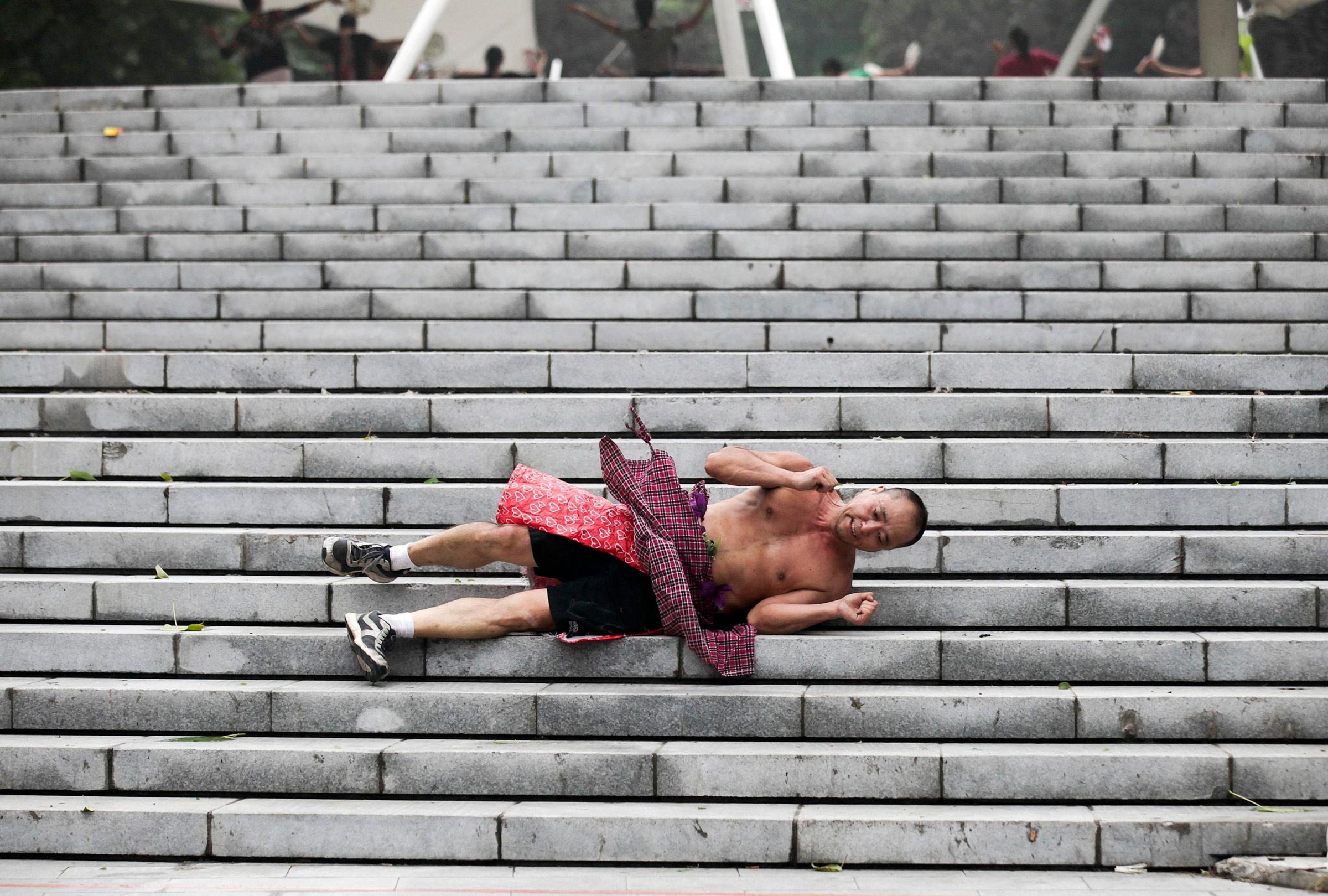 Li Zhiheng, an amateur athlete, holds up his hands as he rolls down a stairway during a morning exercise at a park in Xi'an, Shaanxi province on Sept. 11, 2014.