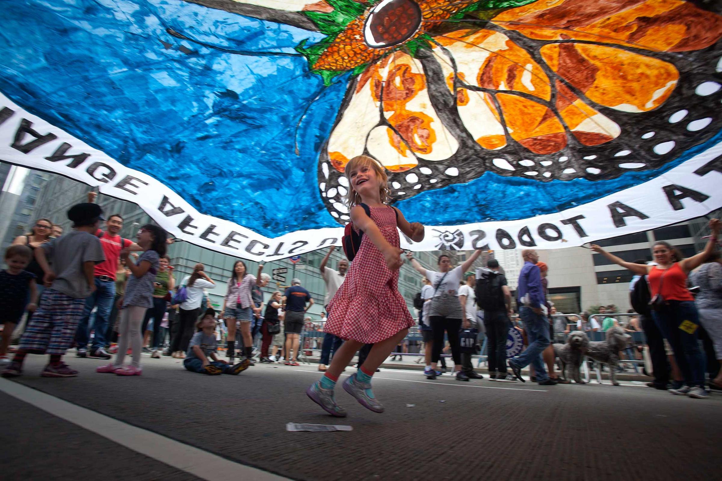 A girl dances under a protest parachute as people take part in the "People's Climate March" down 6th Ave. in the Manhattan borough of New York