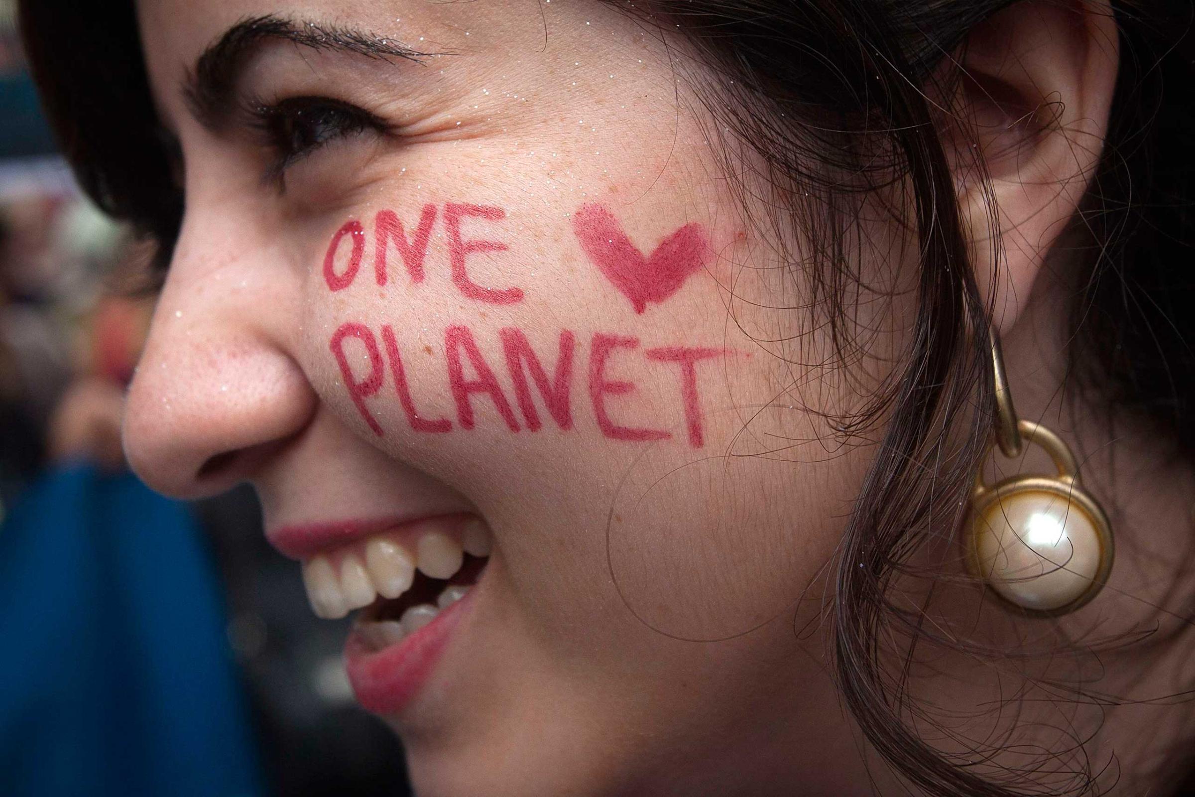A protester with "One Planet" drawn on her face takes part in the "People's Climate March" down 6th Ave. in the Manhattan borough of New York