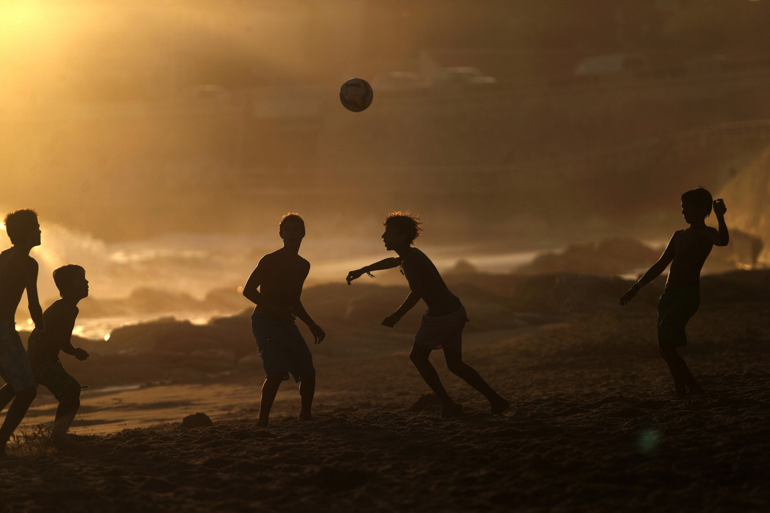 Youngsters play soccer as the sun sets at the Carcavelos beach in Cascais, Portugal on Sept. 2, 2014.