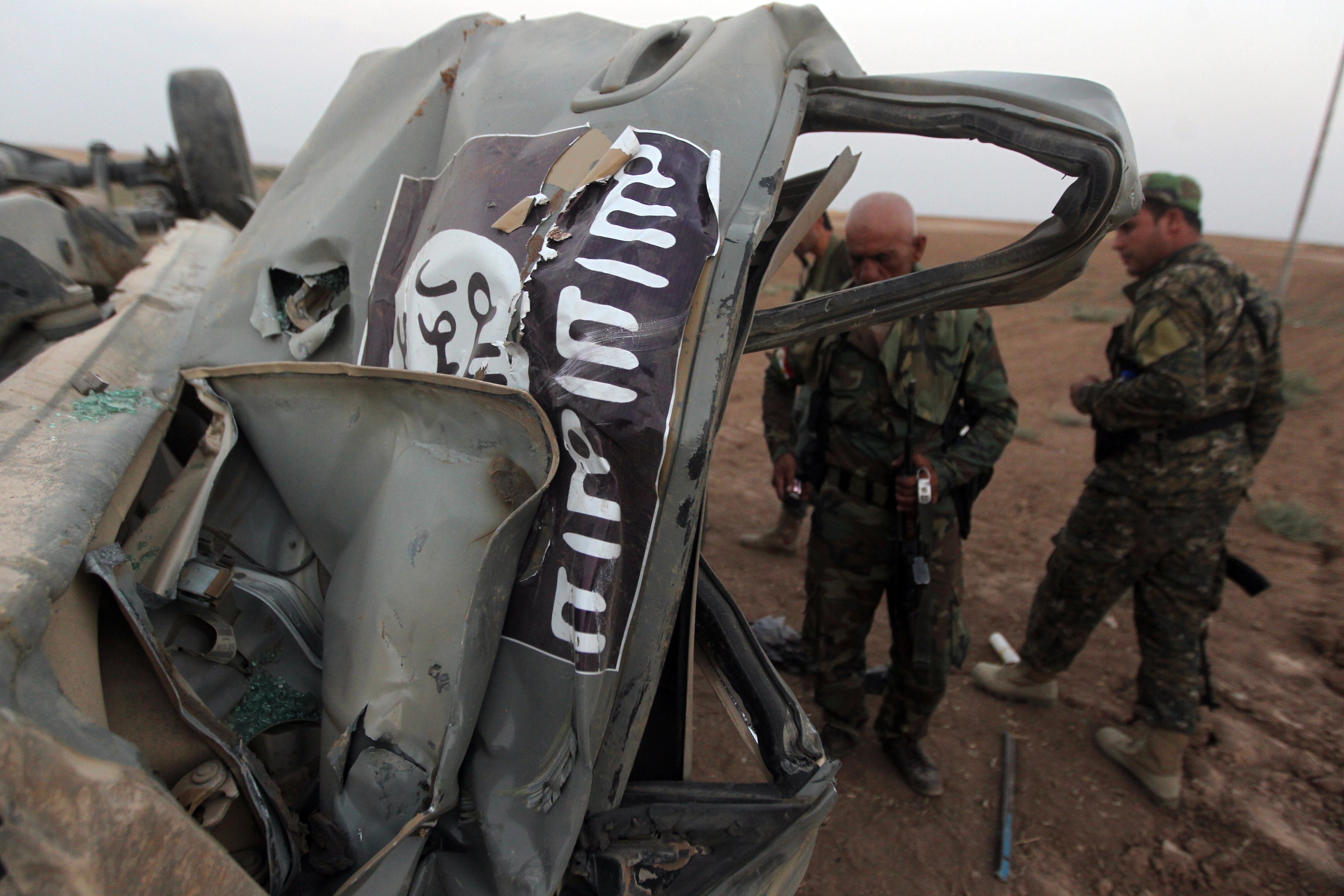 Kurdish fighters inspect an ISIS vehicle, bearing a jihadist flag,  after it was hit by a U.S. air strike in northern Iraq last month. (Ahmad Al-Rubaye—AFP/Getty Images)