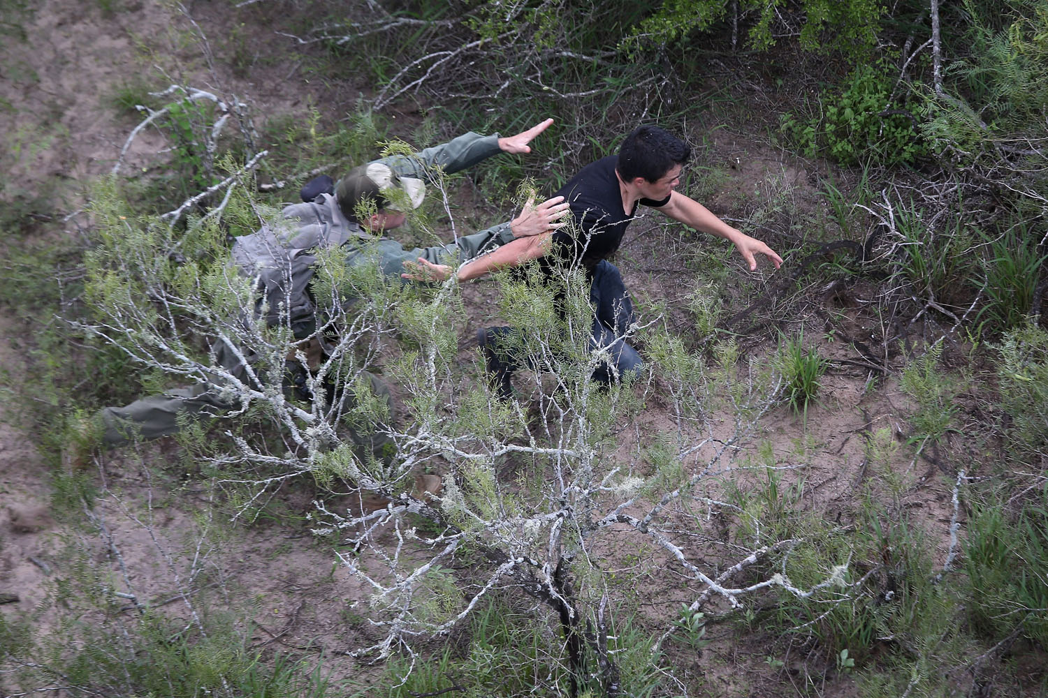 Sept. 9, 2014.  A U.S. Border Patrol agent tries to tackle an undocumented immigrant in dense underbrush near Falfurrias, Texas. Thousands of migrants continue to cross illegally from Mexico into the United States, and Texas' Rio Grande Valley has more traffic than any other sector of the U.S.-Mexico border.