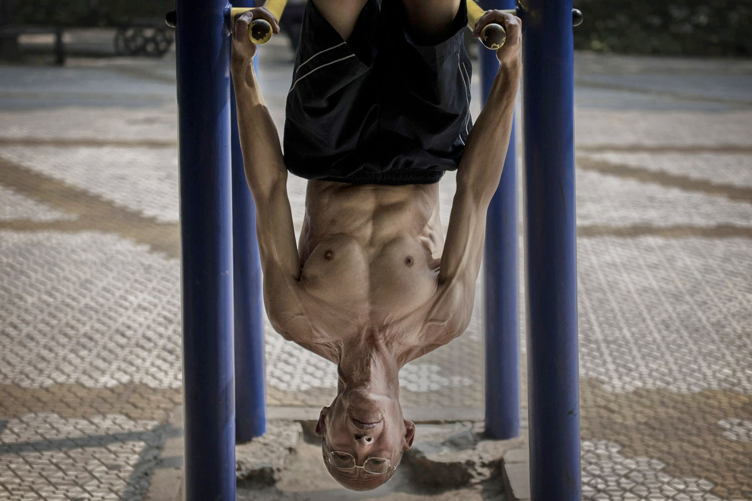 Sept. 10, 2014.  A Chinese man holds himself upside down as he exercises on bars at a park in Beijing, China.