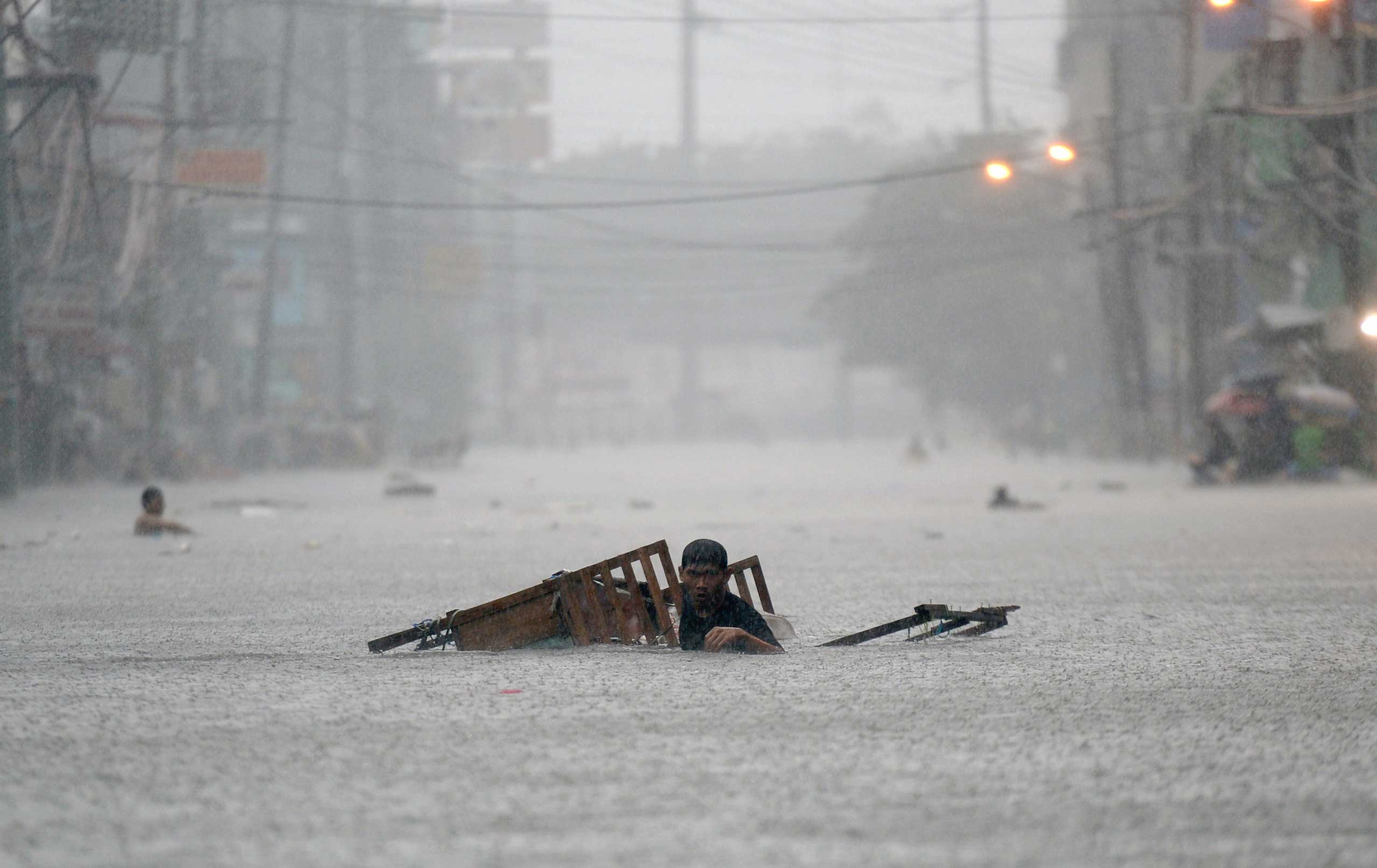 Sept. 19, 2014. A resident tows his vending stall as he wades through a flooded street during heavy rains brought on by tropical storm Fung-Wong in Manila, the Philippines.