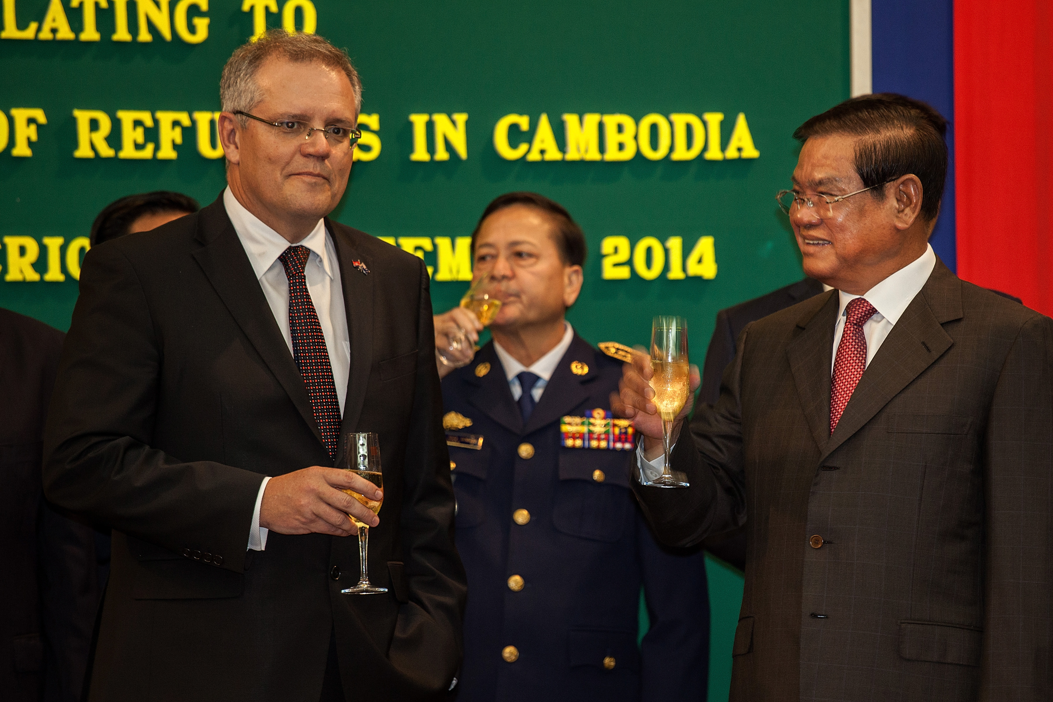 Australian Immigration Minister Scott Morrison and Cambodian Interior Minister Sar Kheng hold a flute of champagne after signing a deal to resettle refugees from Australia to Cambodia at the Ministry of Interior on September 26, 2014 in Phnom Penh, Cambodia. (Omar Havana—Getty Images)