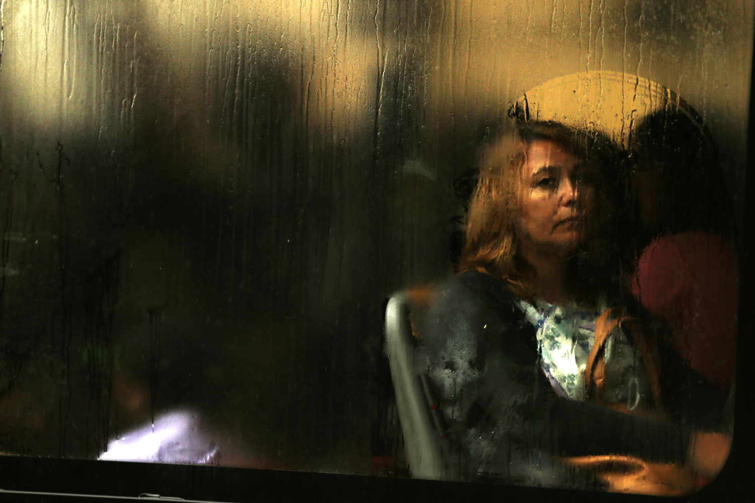 Sept. 10, 2014. A woman looks through the window of a packed bus departing with commuters during a partial strike by Lisbon's subway workers, in Lisbon. The subway staff walked off the job during the morning rush hour in a protest against pay cuts and the company's possible privatization. The strike brought misery for commuters who faced long queues for buses in the rain.