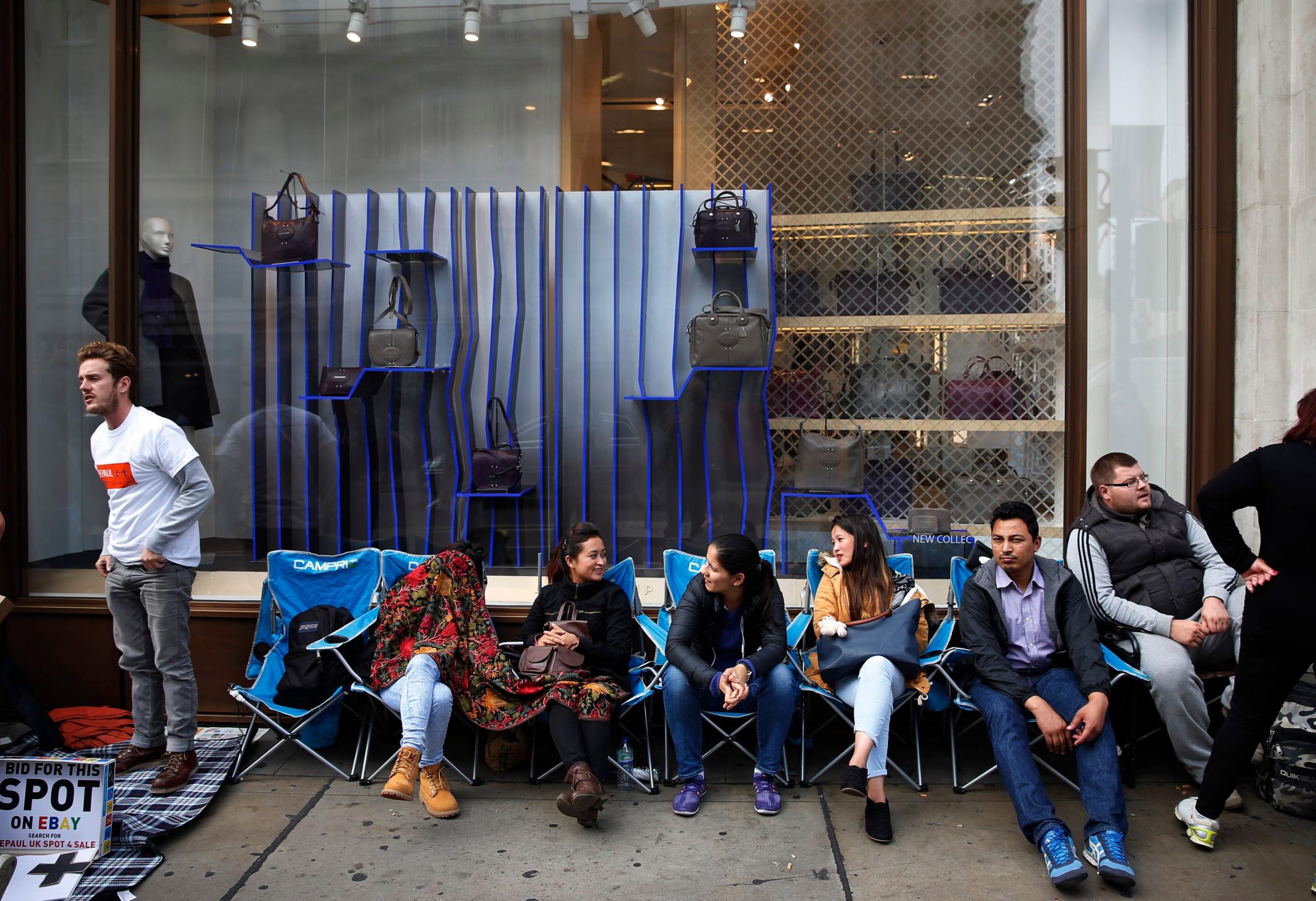 People pass time as they wait outside an Apple store for the iPhone 6 and 6 Plus in London on Sept. 17, 2014.