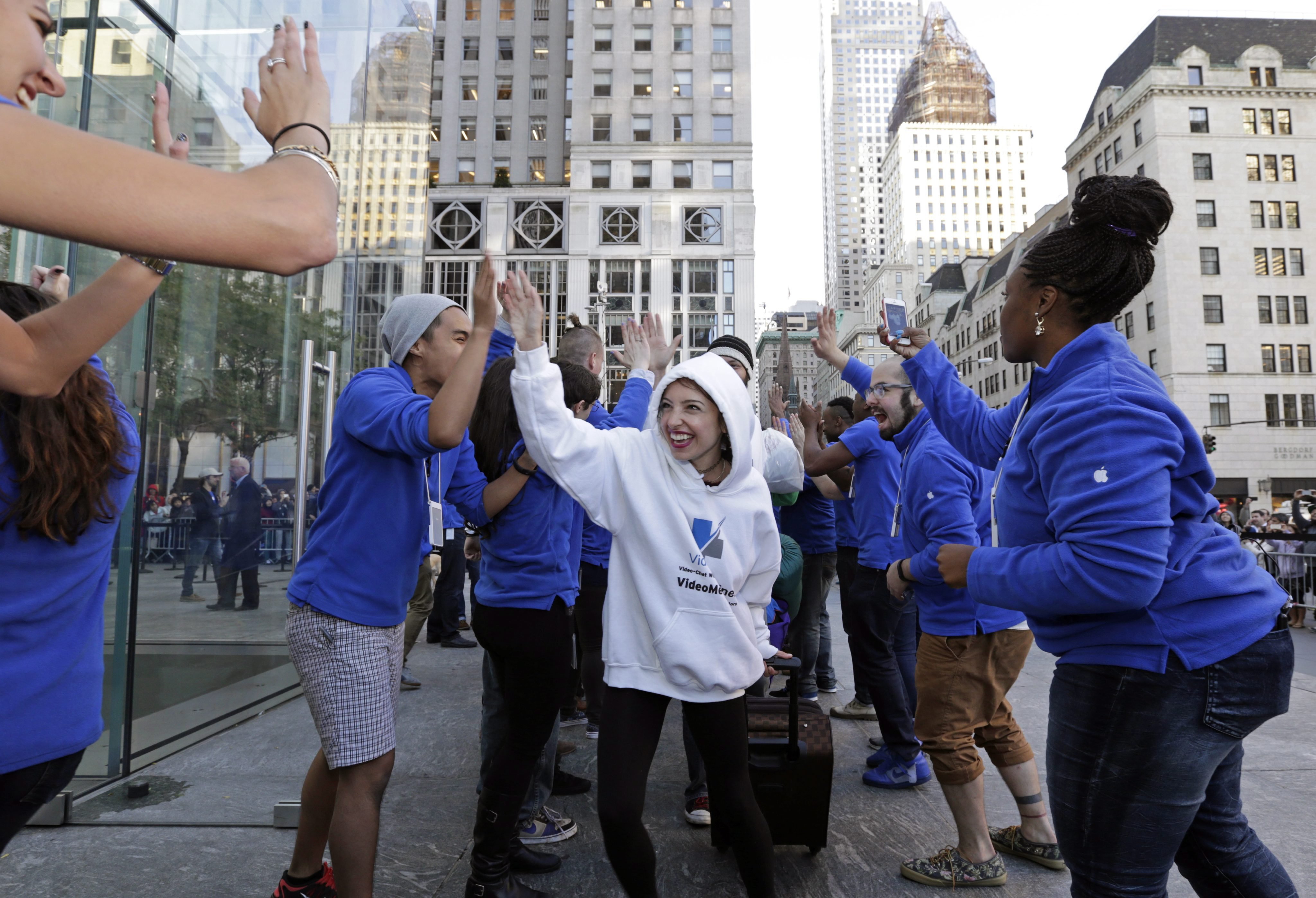 After being first in line for 19 days, Moon Ray, from Jackson, Miss. runs the gauntlet of Apple store workers as she enters the Fifth Avenue Apple store in New York on Sept. 19, 2014.
