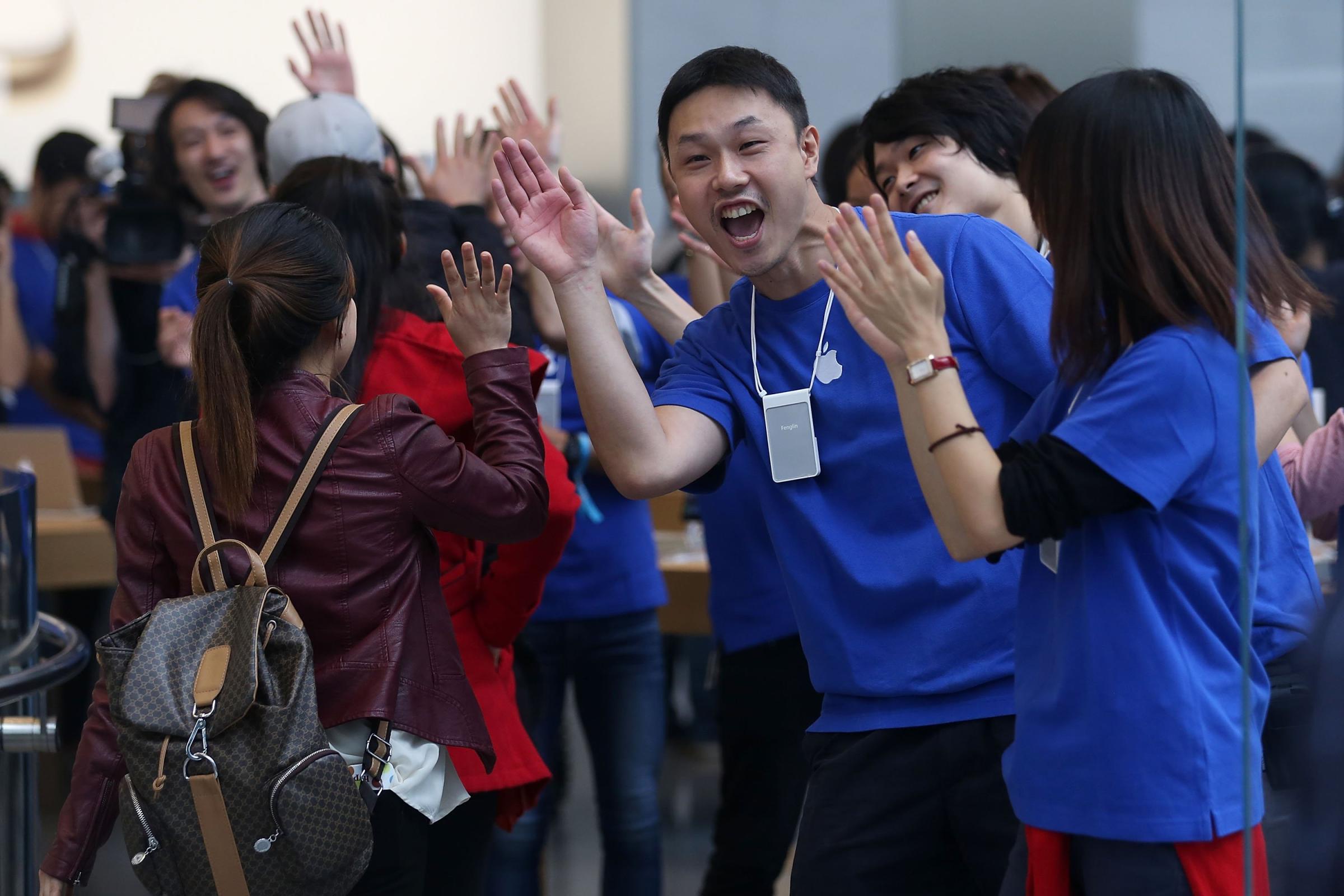 Apple store staff high five customers as they enter the store in Tokyo on Sept. 19, 2014.