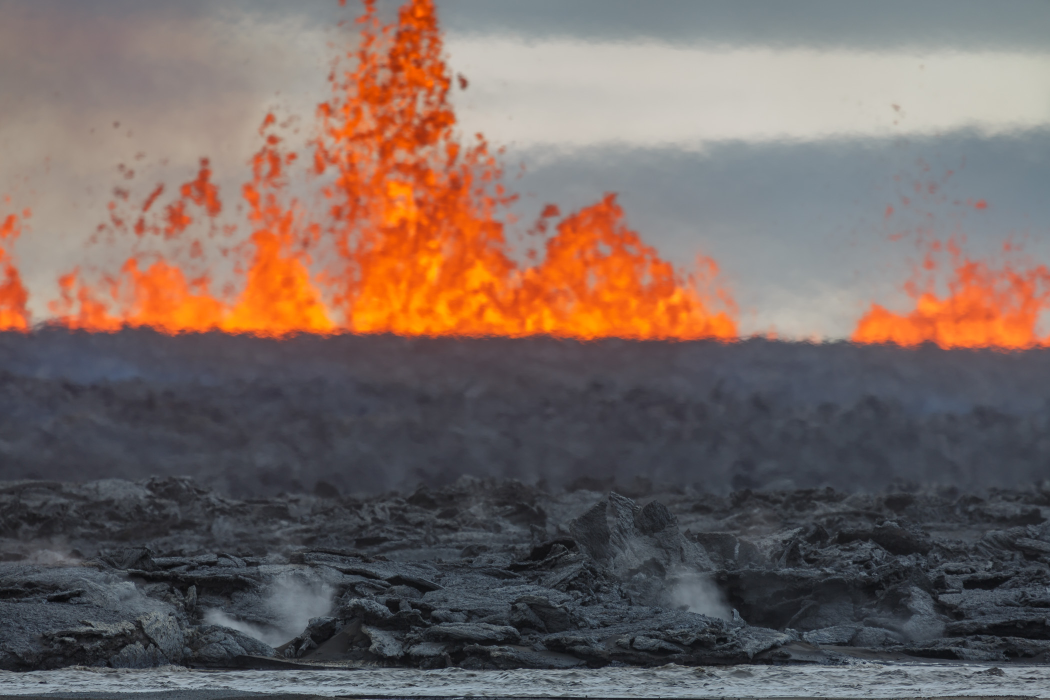 Lava fountain and black lava in the foreground. Bardarbunga / Holuhraun eruption. Iceland Central Highlands 2014.